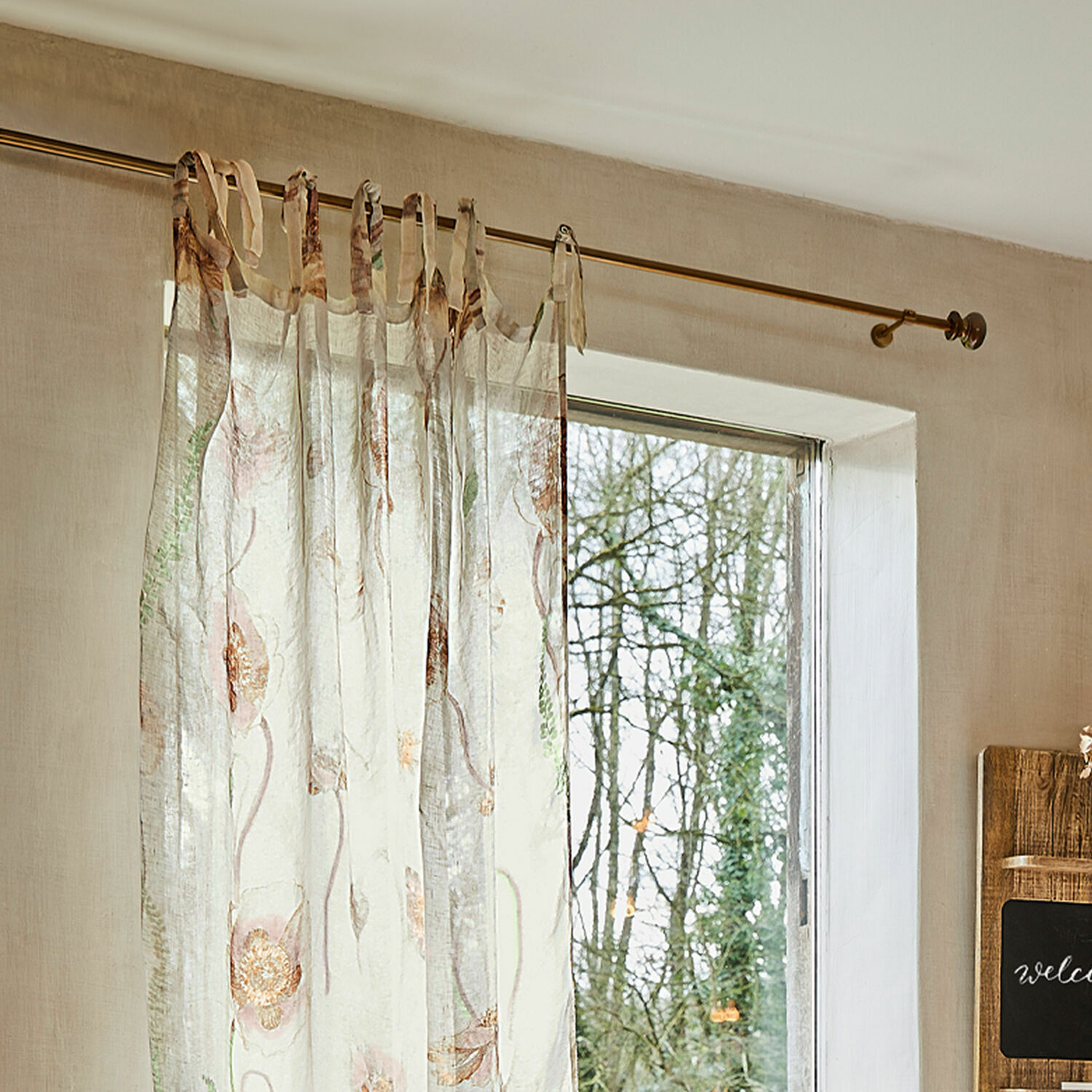 Tringle à rideaux Henderson Rideau transparent avec motif floral délicat aux couleurs pastel suspendu à une tringle à rideau.