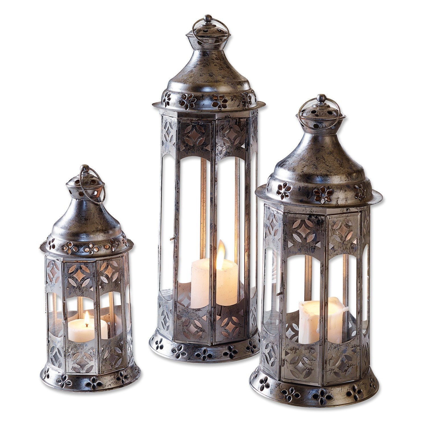 Lot de 3 lanternes Aylin Ensemble de trois lanternes en métal argenté avec motifs décoratifs et bougies allumées à l'intérieur