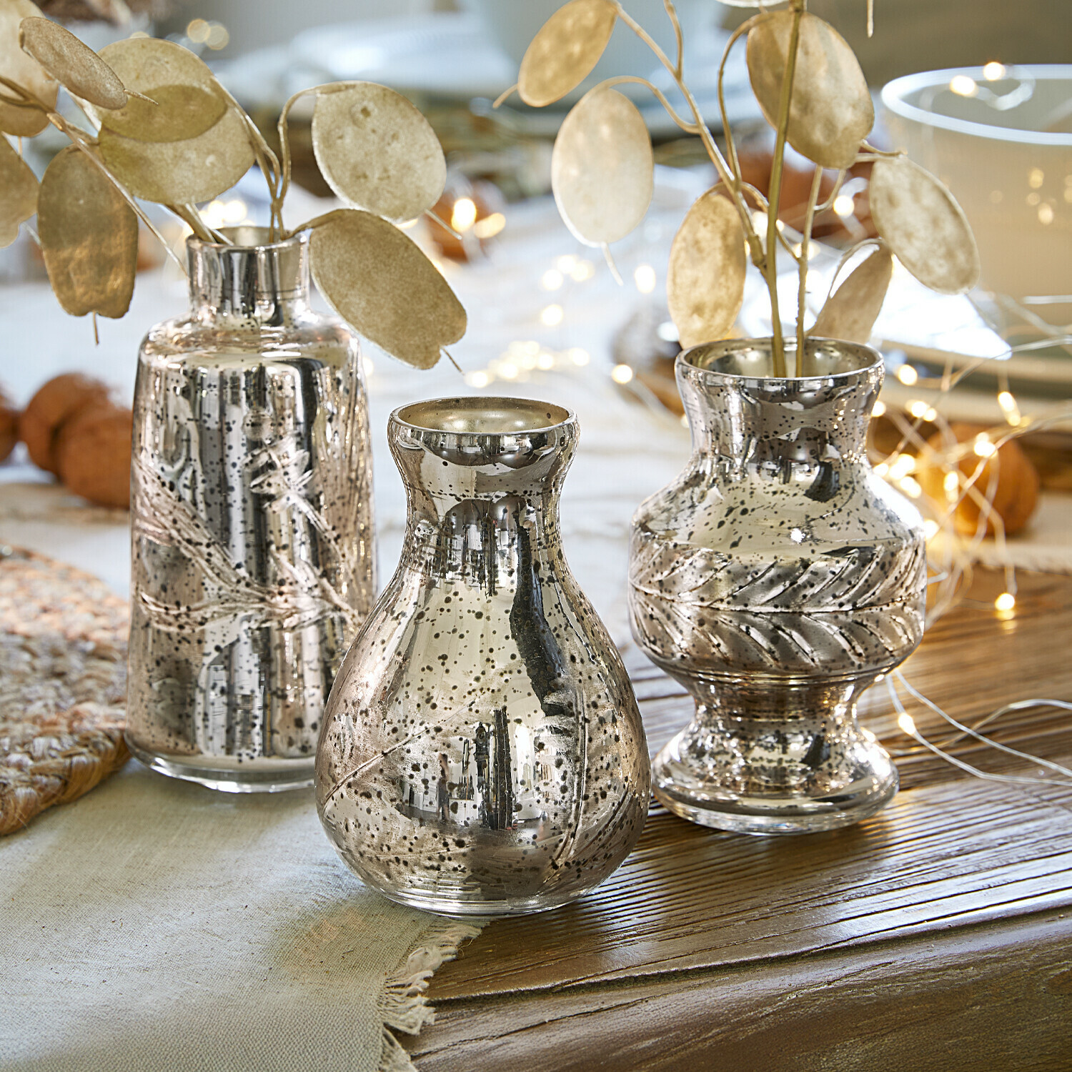 Lot de 3 vases Briolique Ensemble de trois vases en verre argenté avec motif de feuilles décoratives sur une table en bois