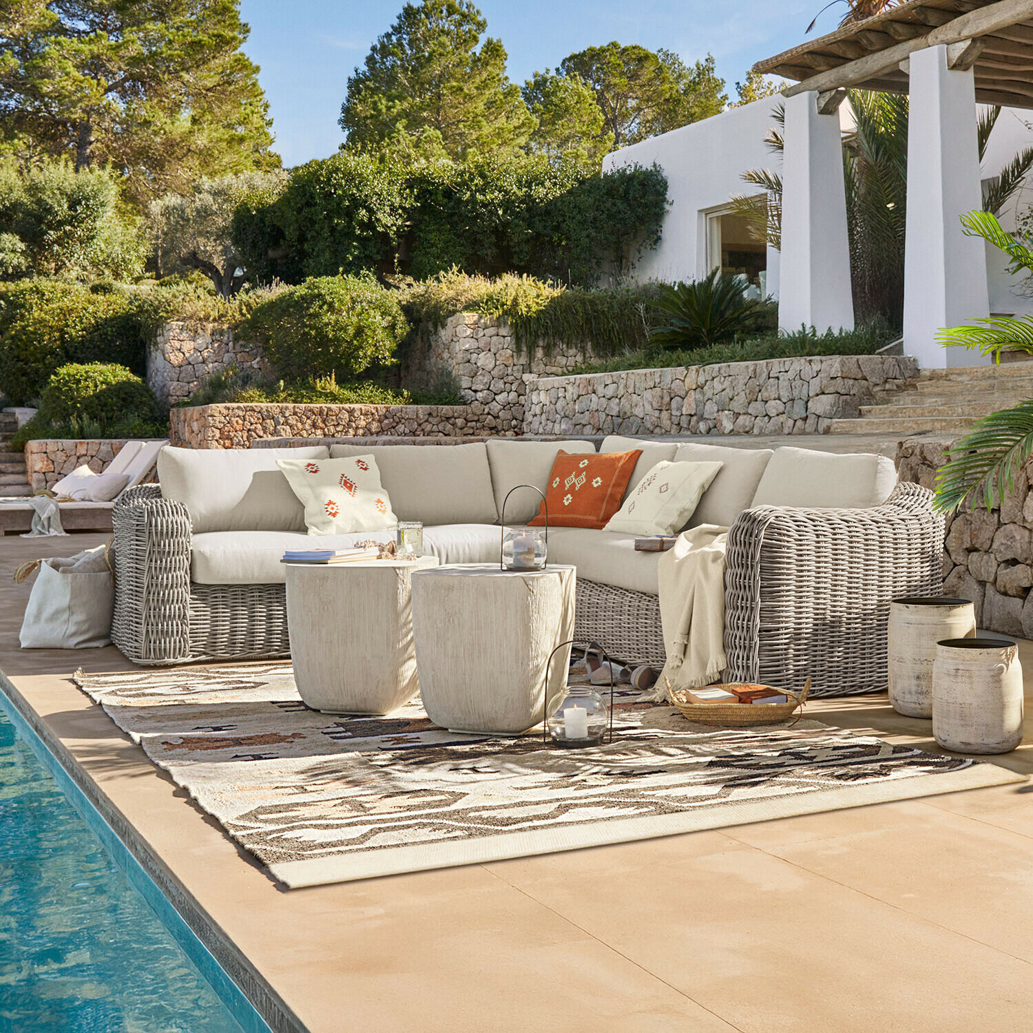 Ensemble de mobilier d'extérieur avec canapé en rotin beige et coussins décoratifs au bord de la piscine