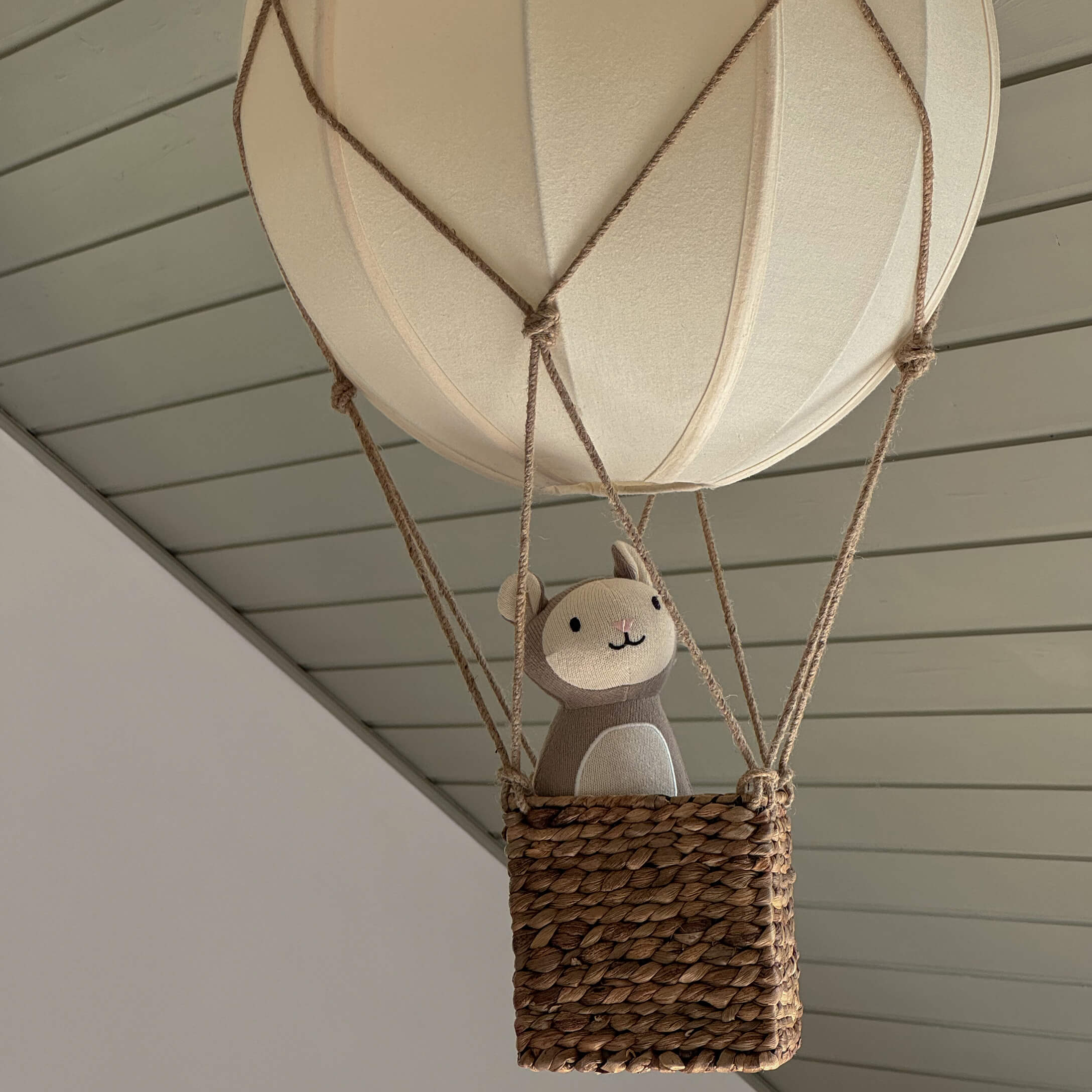 Ballon suspendu décoratif avec panier en osier et peluche beige dans un intérieur moderne