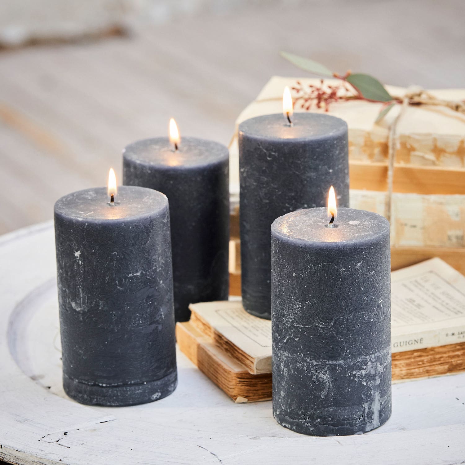 Lot de 4 bougies Braga Quatre bougies noires en cire sur une table blanche avec des livres, décoration intérieure cosy