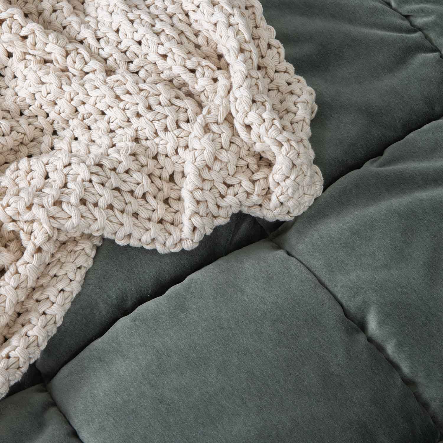 Couverture épaisse en coton crème tricotée à la main sur un matelas vert doux pour détente