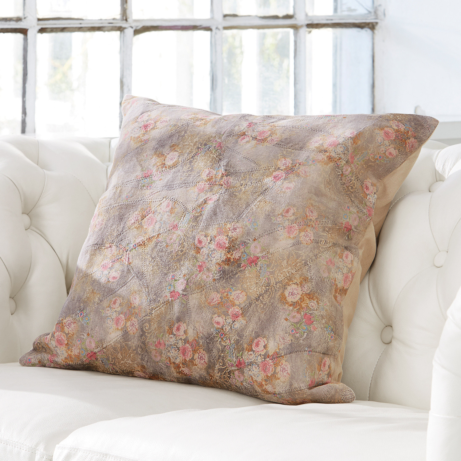 Coussin Veronique Coussin décoratif avec motif floral pastel sur fond clair posé sur un canapé blanc
