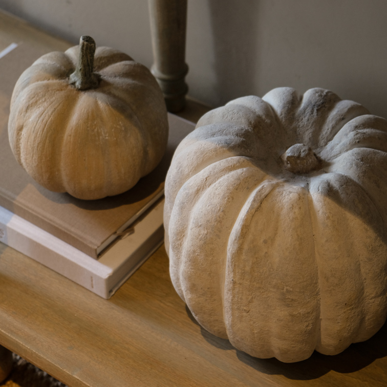 Citrouilles décoratives en béton aux tons naturels sur une table en bois, décoration d'automne intérieure