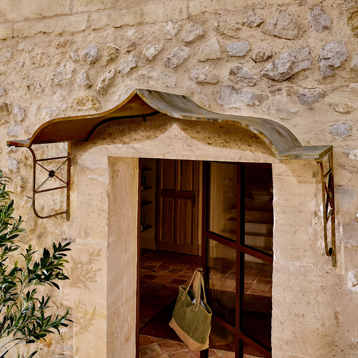 Auvent en métal rustique au-dessus d'une porte en pierre, protection contre la pluie