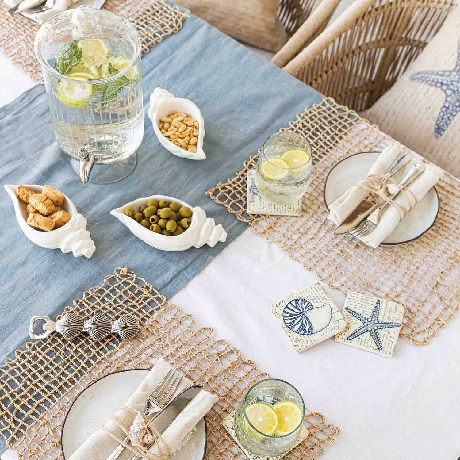 Table d'été décorée style marin avec bols en céramique coquillage blancs remplis d'amuse-bouches et limonade