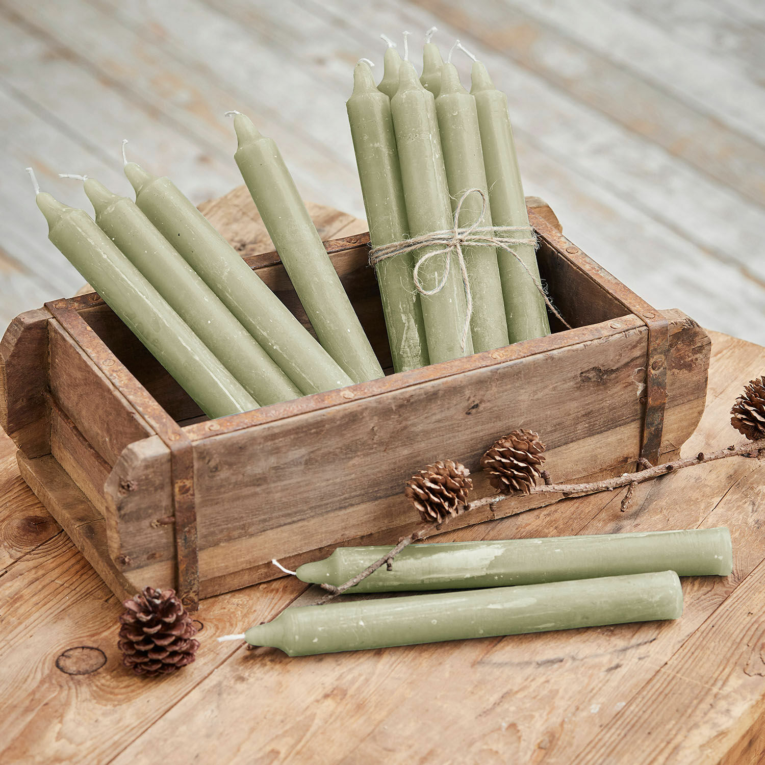 Lot de 12 bougies Bauceau Lot de bougies vertes en cire dans une boîte en bois sur une table rustique avec des pommes de pin