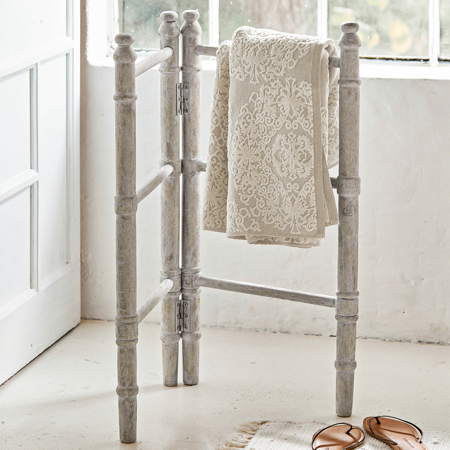 Porte-serviettes Cumana Porte-serviettes en bois blanc vieilli avec serviette beige à motif décoratif dans une pièce lumineuse