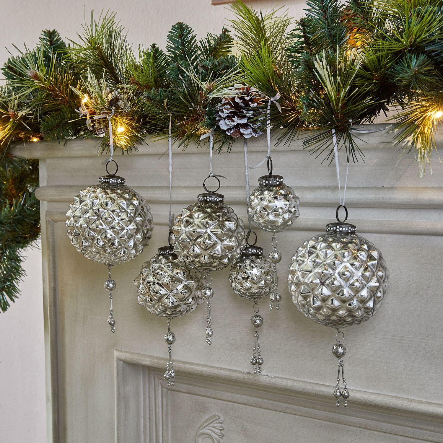 Lot de 6 décorations de Noël Murron Boules de Noël en verre argenté avec décorations suspendues devant une cheminée et des branches vertes éclairées