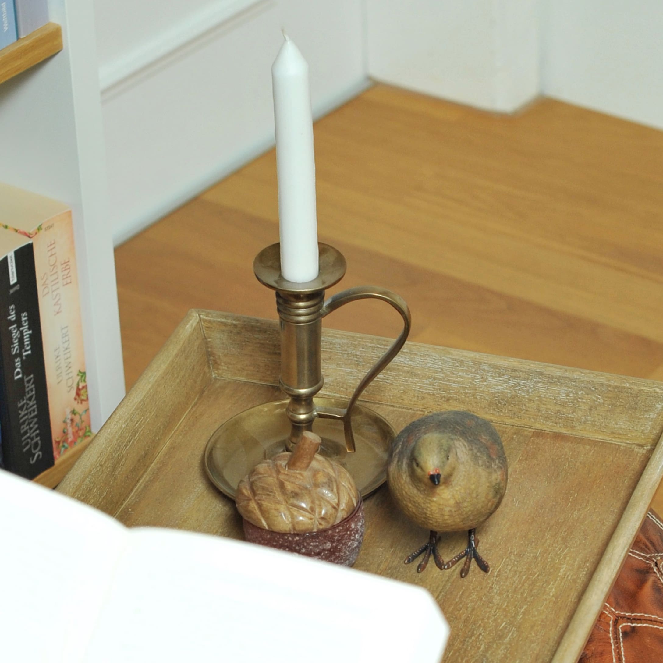 Bougeoir en laiton avec bougie blanche, décoration en bois gland et figurine d'oiseau sur plateau en bois