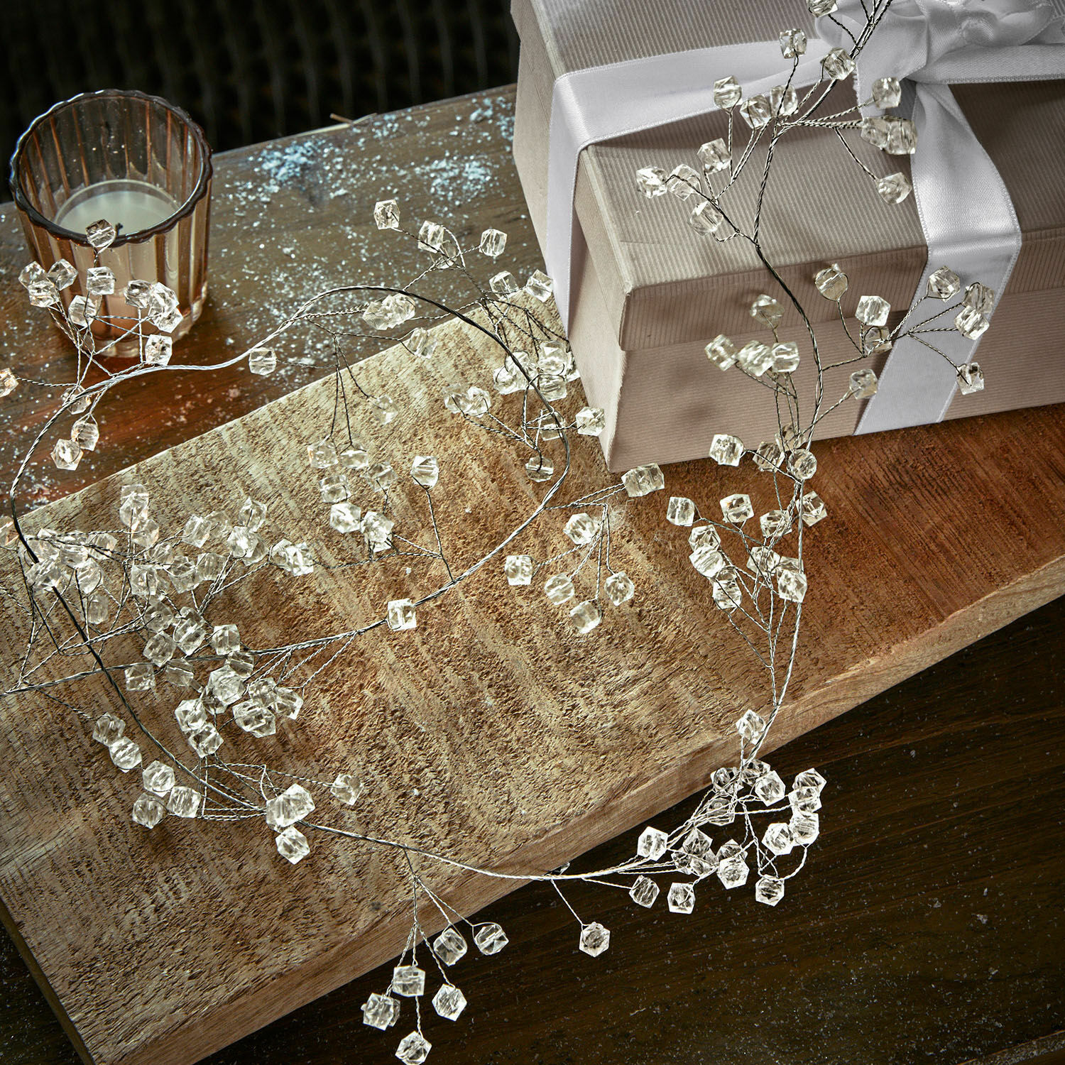 Guirlande Claix Couronne décorative délicate en cristaux transparents sur cadre métallique posée sur une table en bois