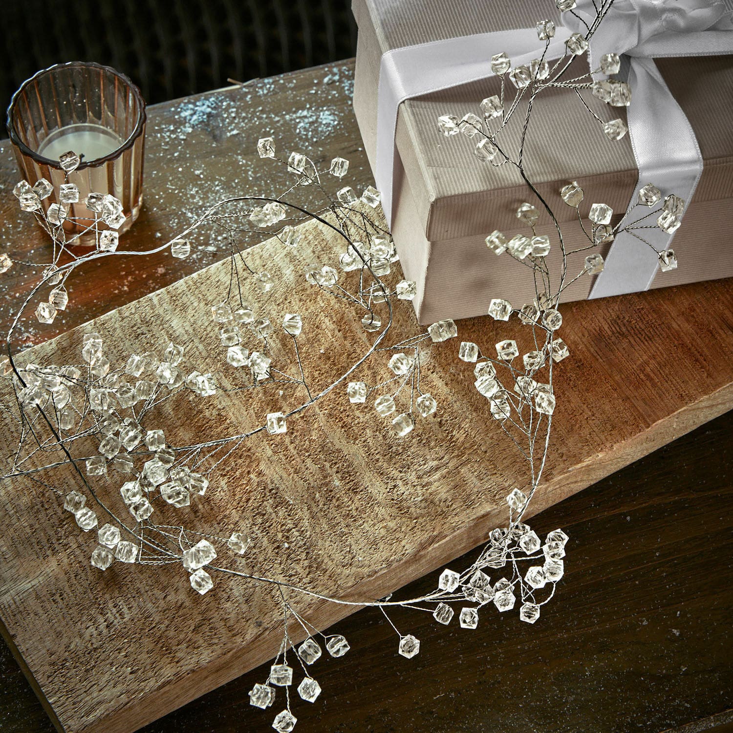 Guirlande Claix Couronne décorative délicate en cristaux transparents sur cadre métallique posée sur une table en bois
