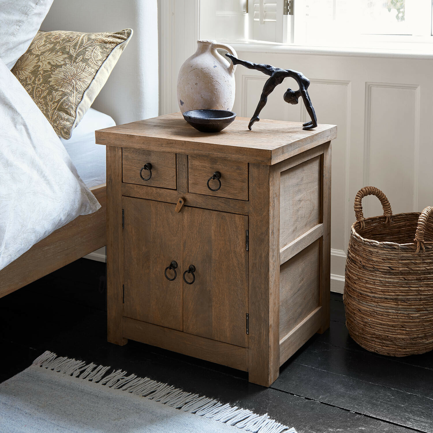 Table de chevet Fenaro Table de chevet en bois naturel avec poignées en métal et objets décoratifs sur le dessus dans une chambre