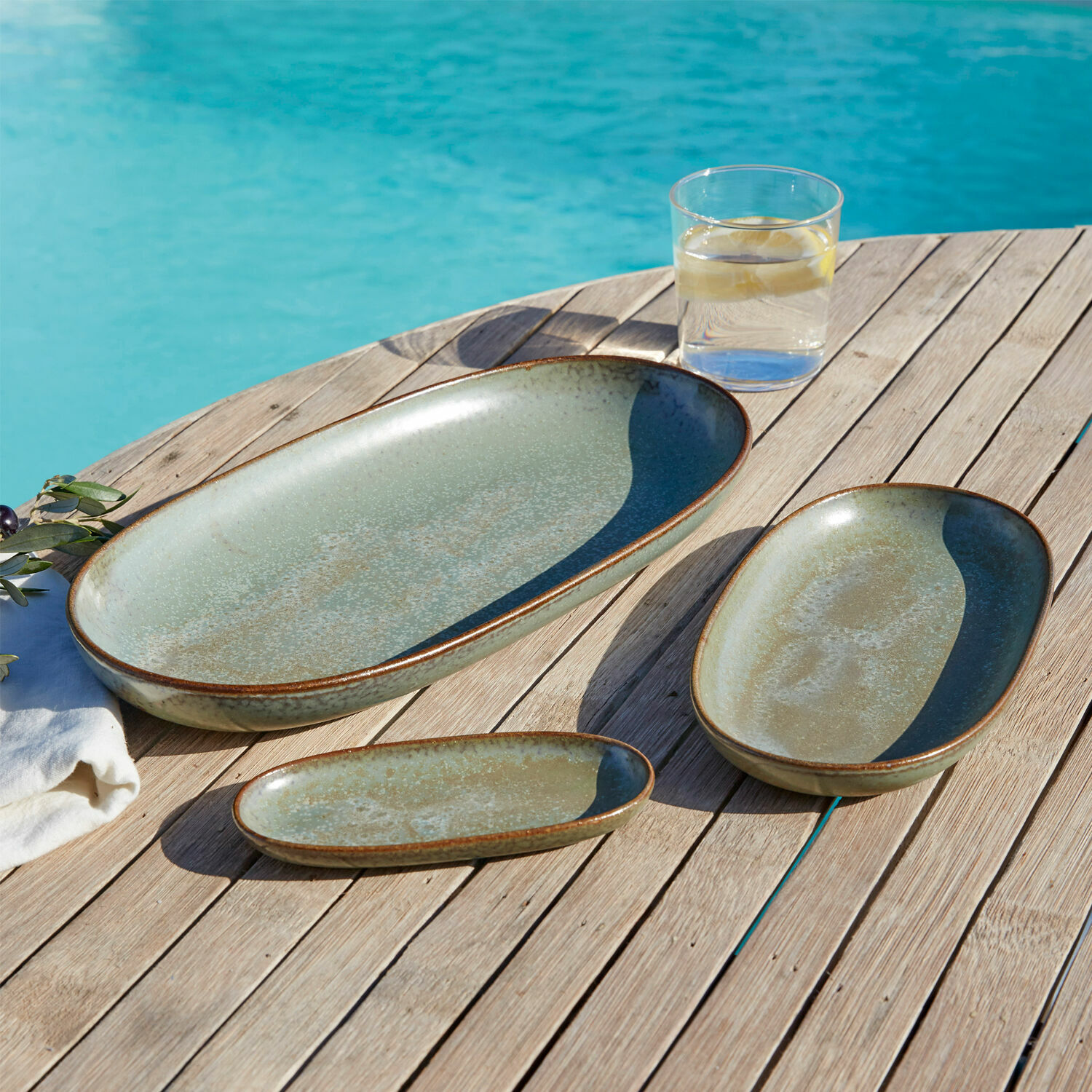 Lot de 3 plateaux de service Biarré Ensemble de trois assiettes en céramique vertes posées sur une table en bois près de la piscine