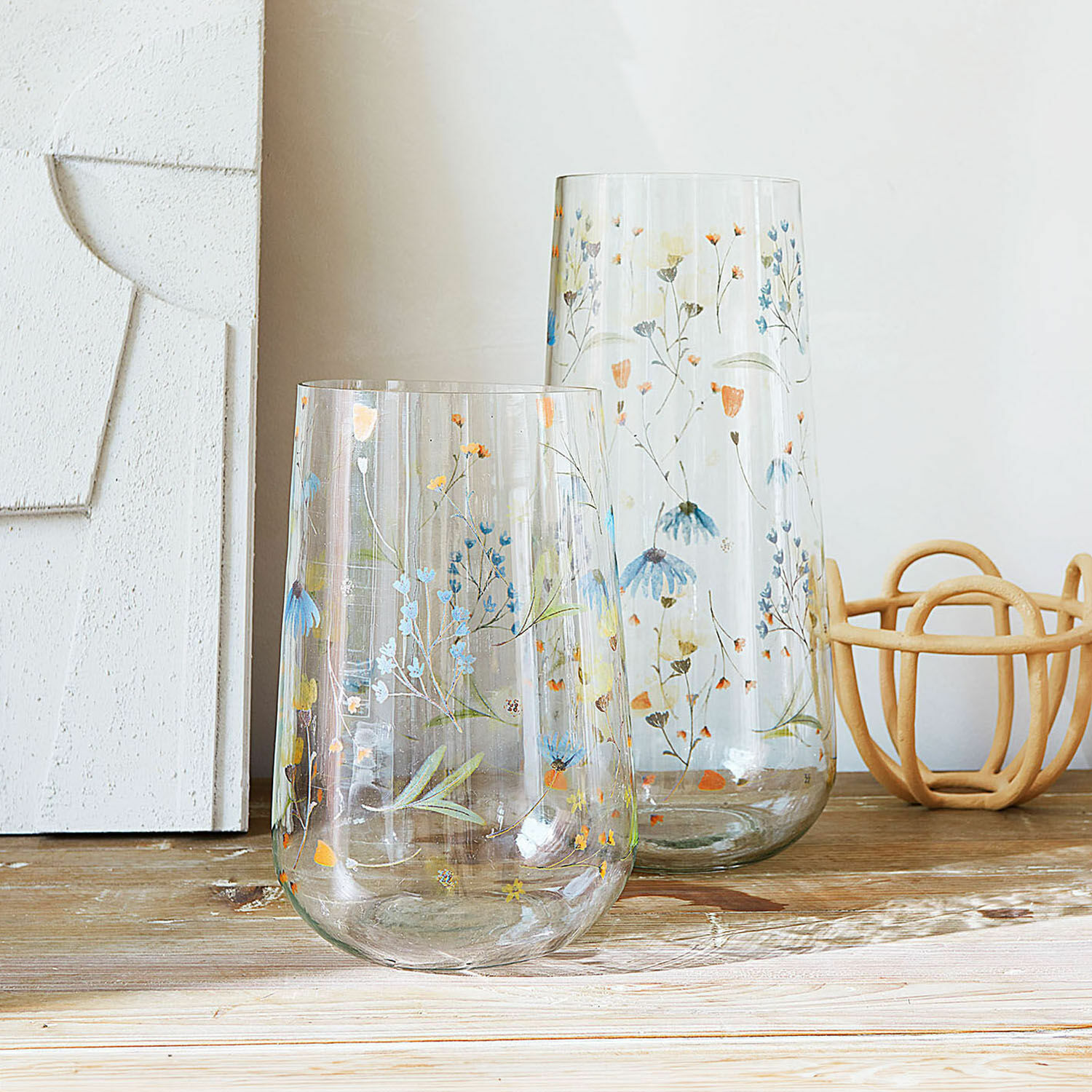 Lot de 2 vases Nervila Deux vases en verre transparent avec motif floral coloré posés sur une table en bois