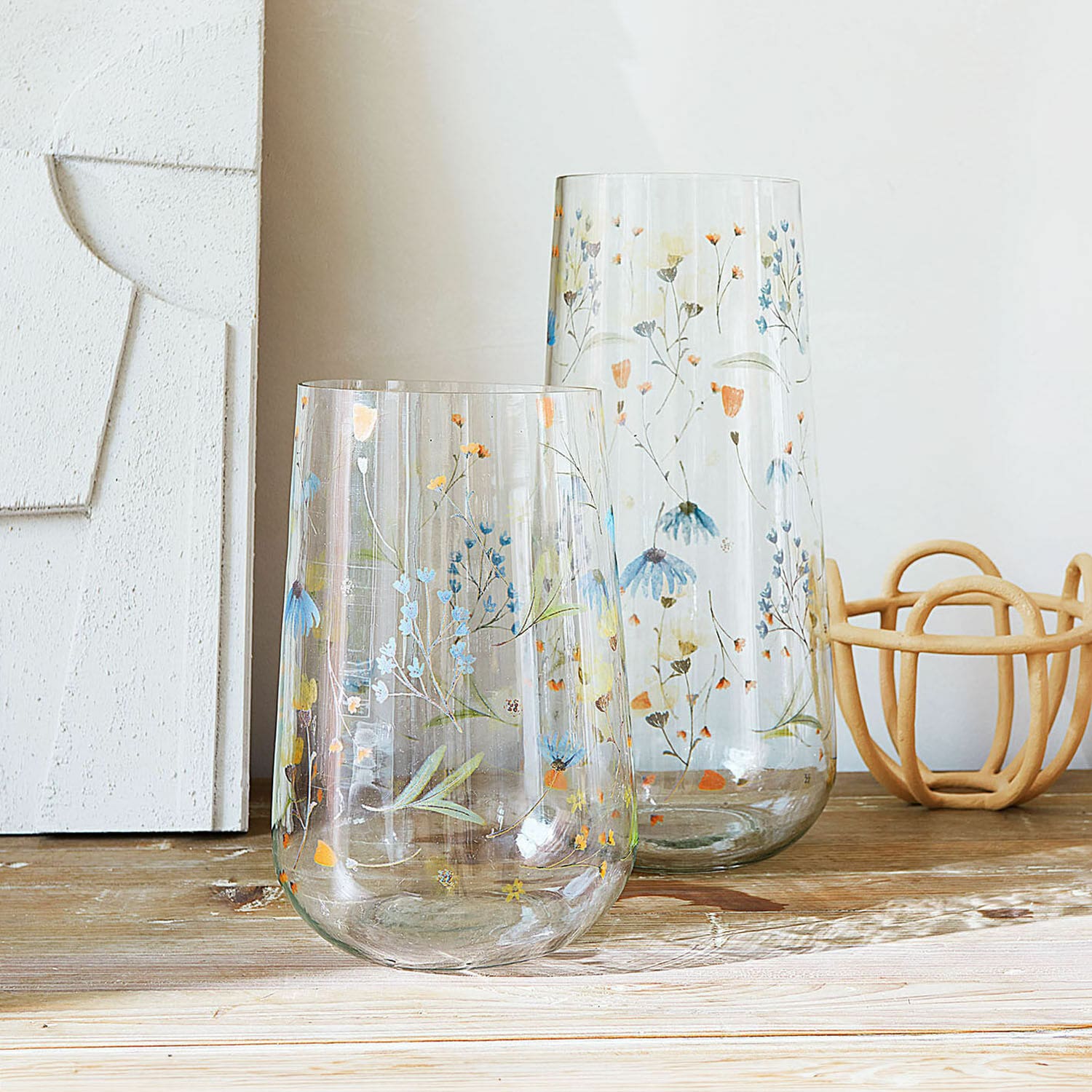 Lot de 2 vases Nervila Deux vases en verre transparent avec motif floral coloré posés sur une table en bois