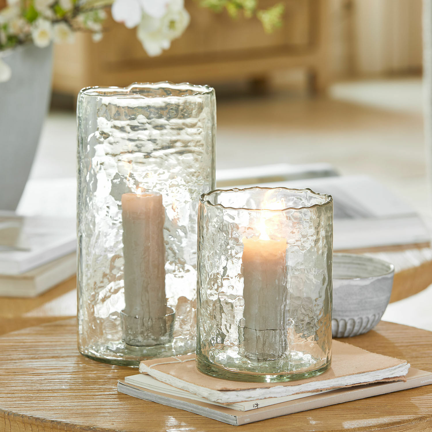 Lot de 2 photophores Querlay Photophores en verre texturé transparent avec bougies blanches sur une table en bois clair
