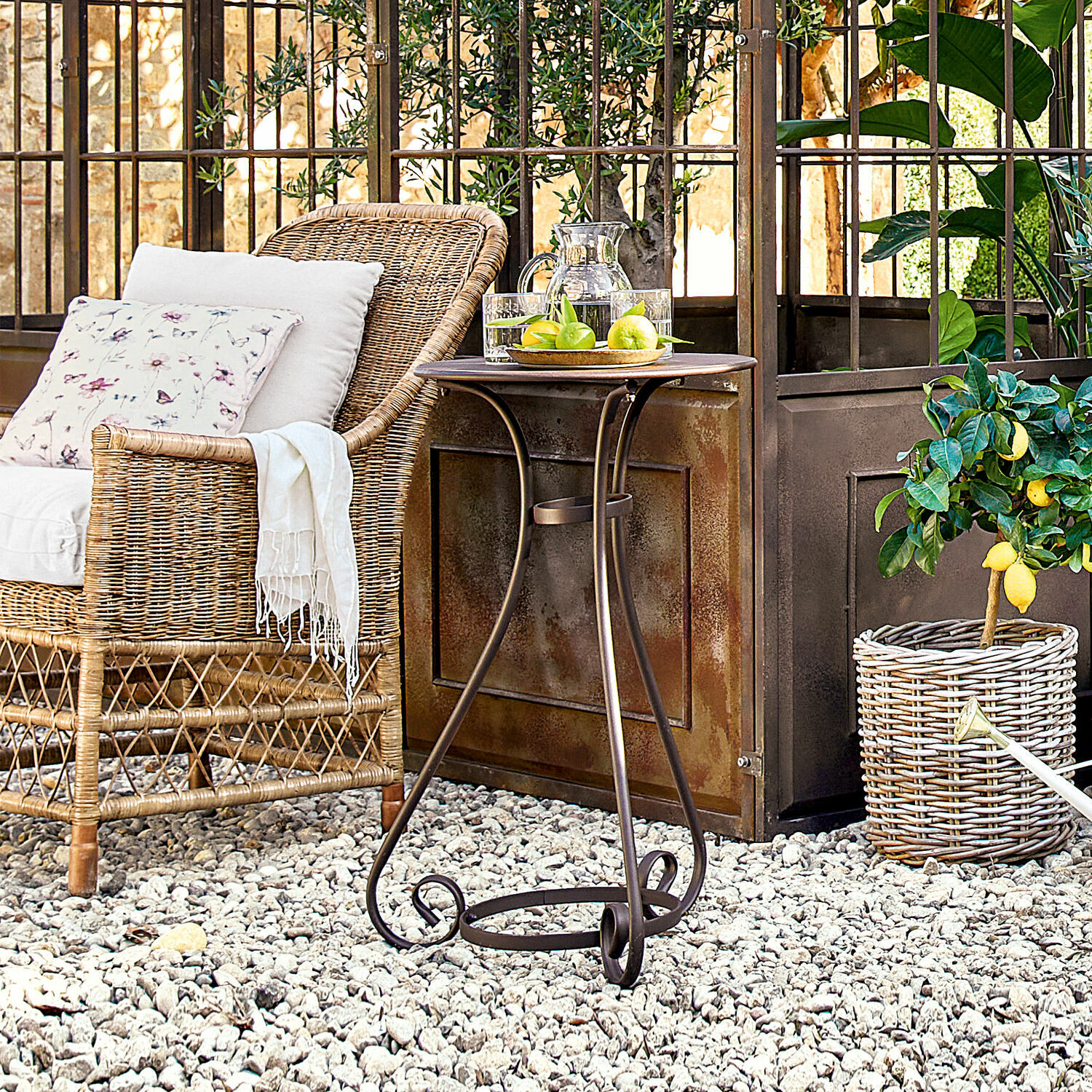 Table d'appoint Savigny Table d'extérieur en métal brun avec pieds décoratifs sur sol en gravier blanc