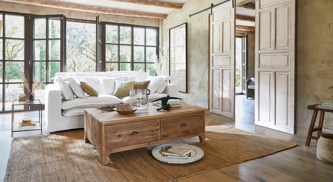 Salon avec canapé blanc et table basse en bois sur tapis naturel, style rustique chaleureux