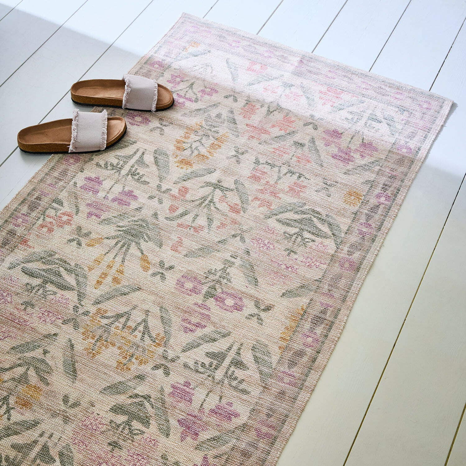 Tapis long Jardin d'Été Tapis à motif floral pastel sur sol clair avec des sandales beiges à franges posées dessus