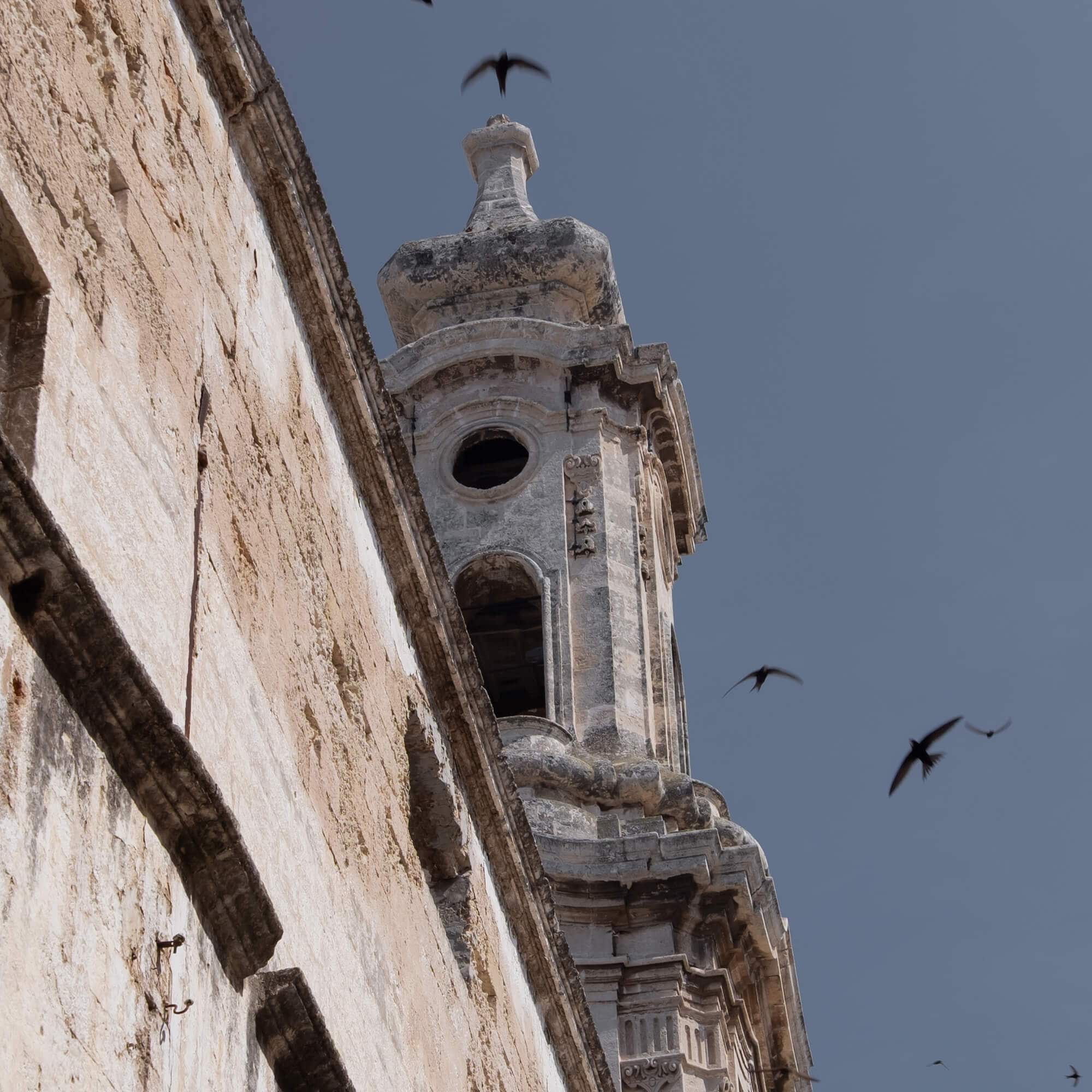 Vue d'une ancienne tour en pierre avec des oiseaux volant dans le ciel