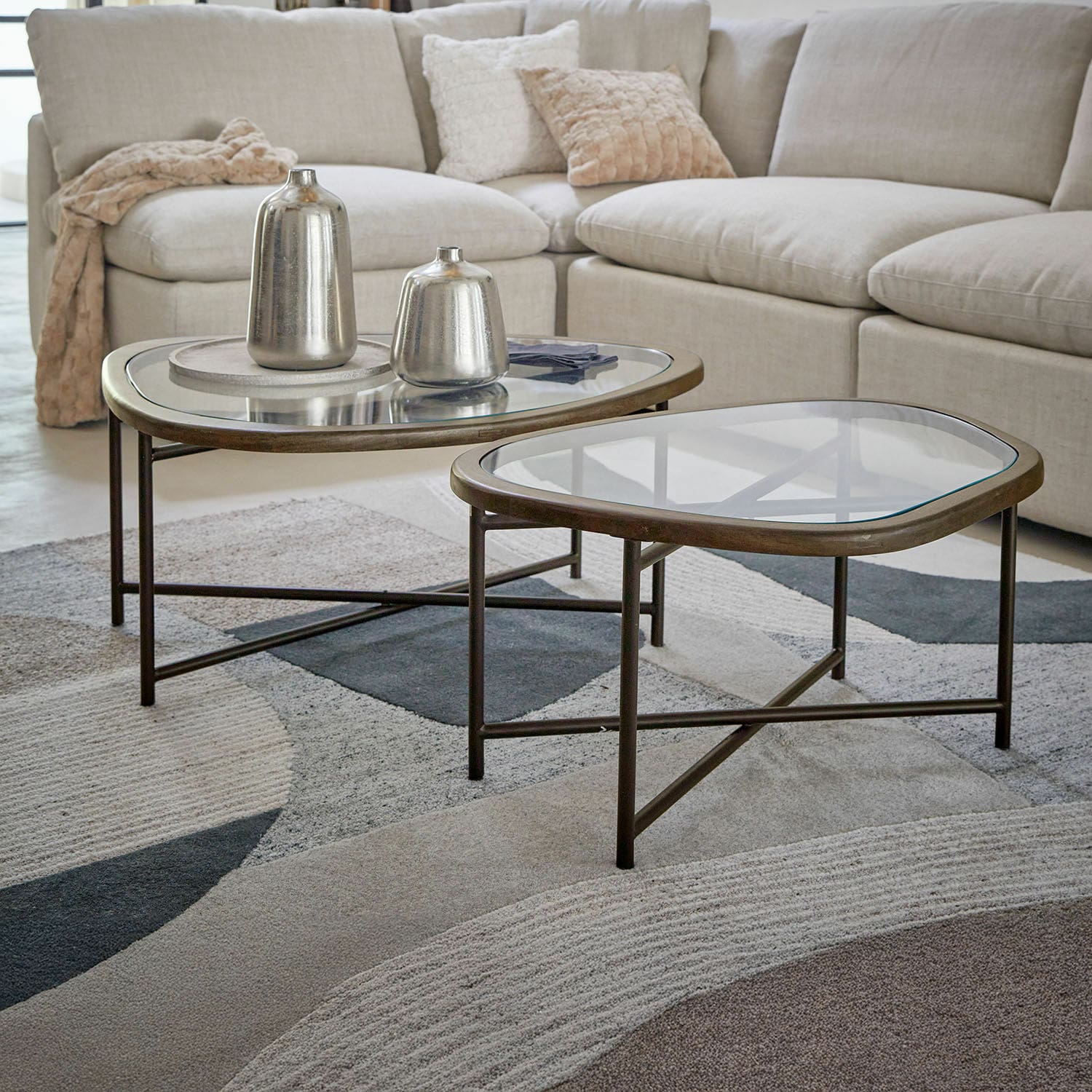 Lot de 2 tables basses Kembria Ensemble de deux tables basses avec cadre en métal et plateau en verre dans un salon avec canapé beige