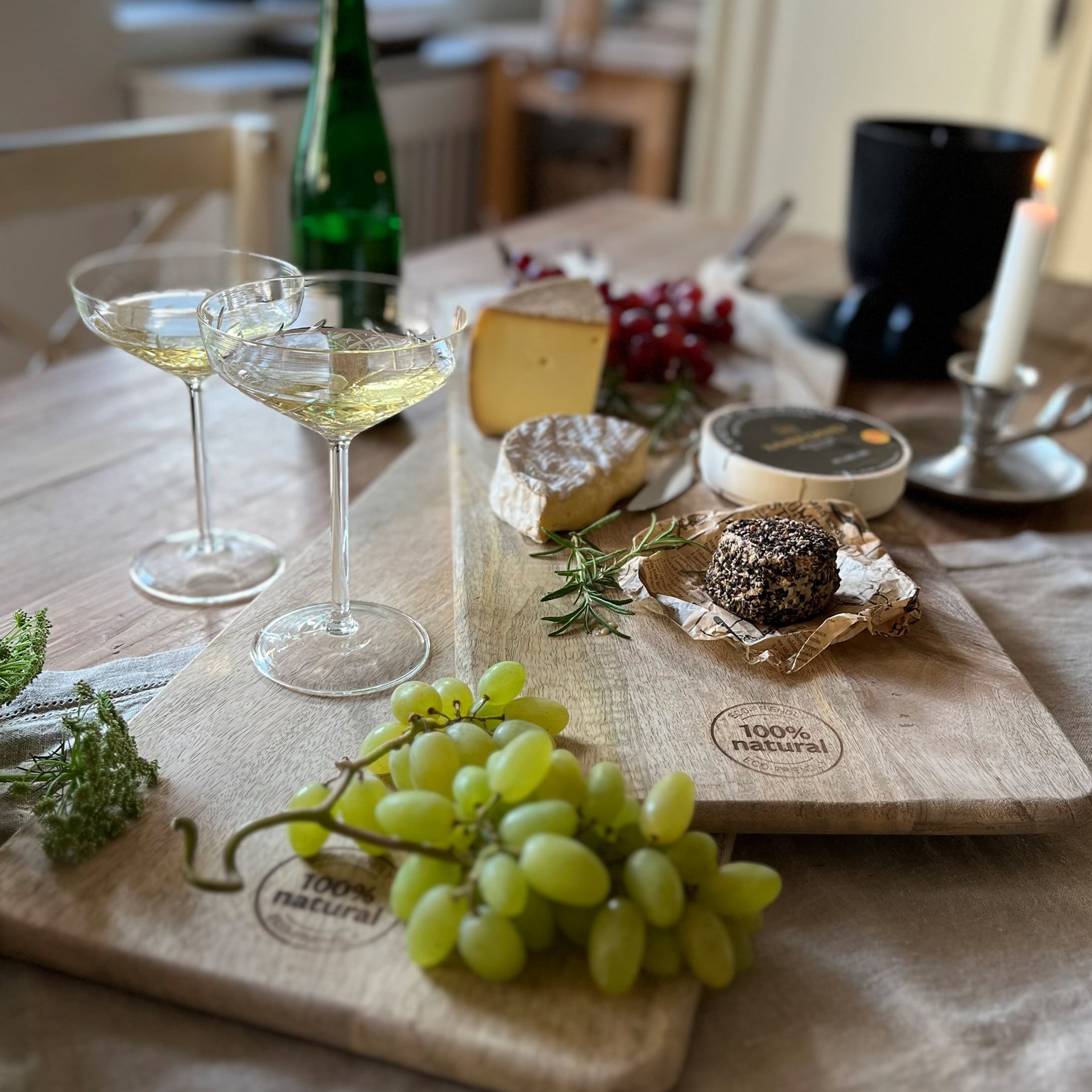 Planche à découper en bois naturel avec raisins, fromages et verres à vin sur une table en bois