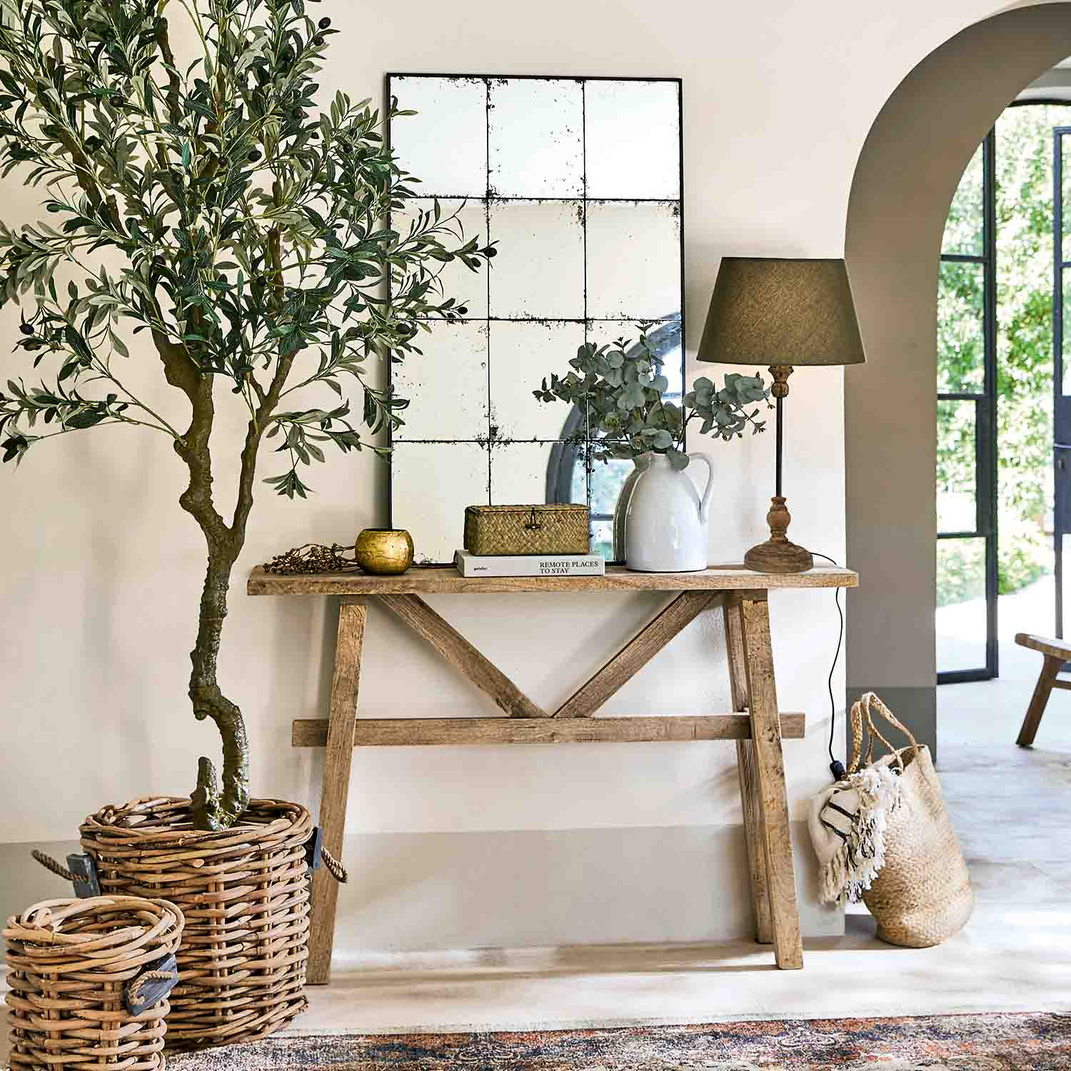 Console en bois avec miroir, lampe et décorations en osier dans un intérieur lumineux et naturel