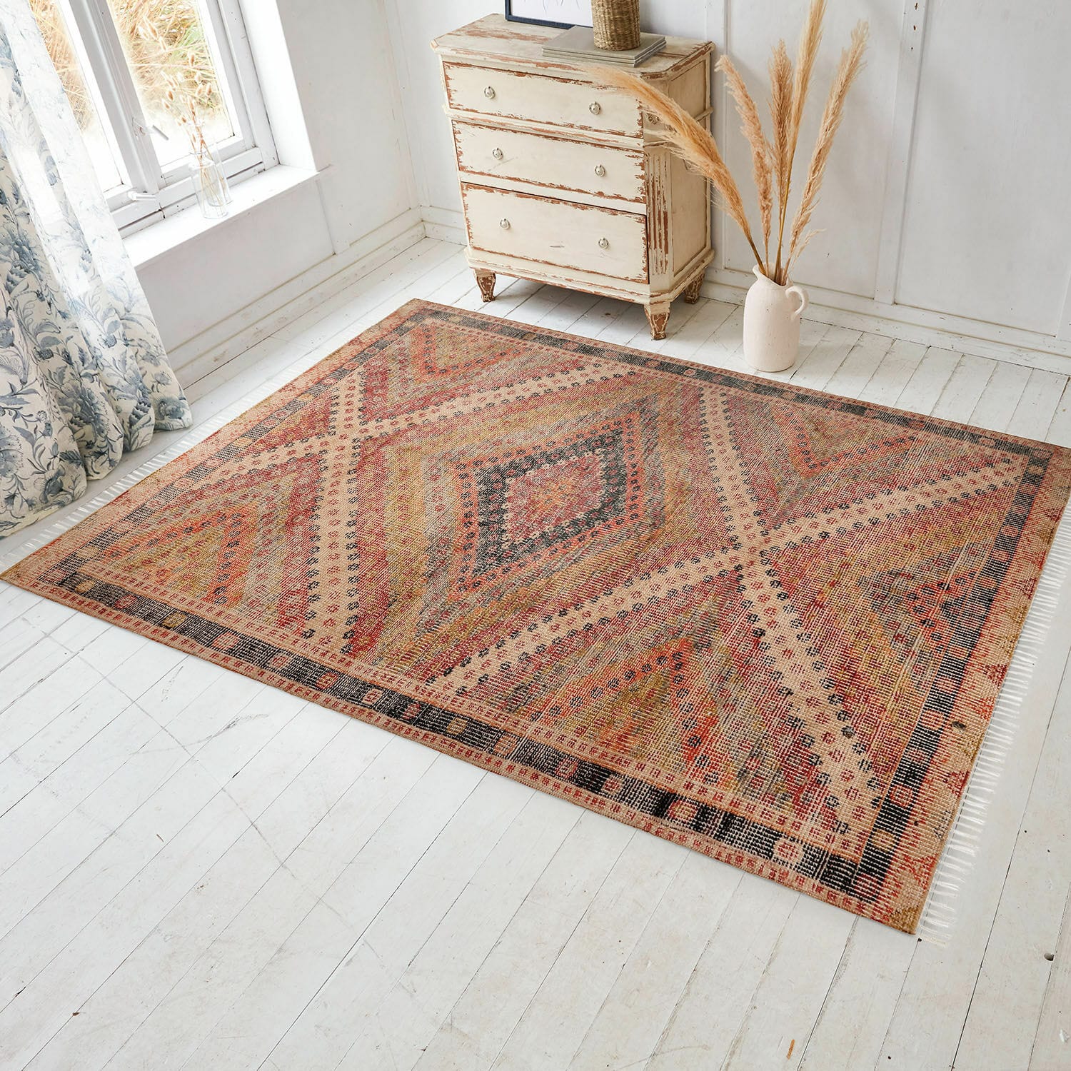 Tapis d’intérieur et d’extérieur Mildura Tapis à motif géométrique aux tons chauds rouge et beige sur un sol clair dans une pièce lumineuse