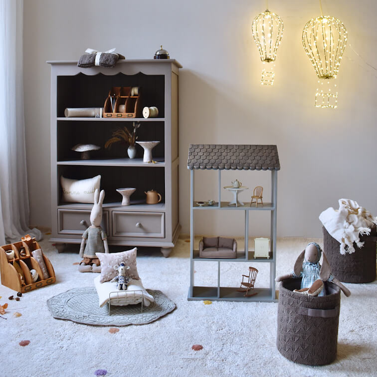 Meuble gris en bois et maison de poupée avec jouets dans une chambre d'enfant chaleureuse avec tapis