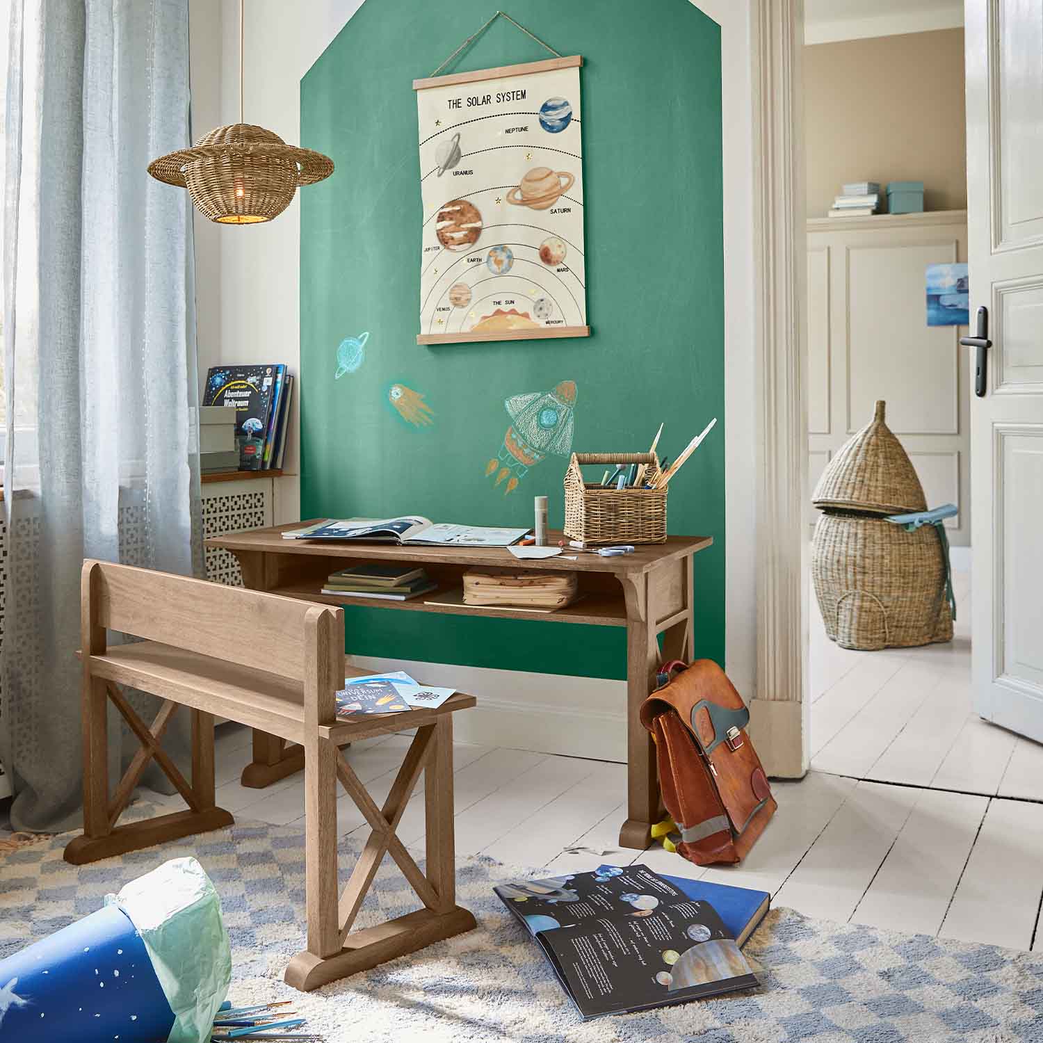 Bureau et banc en bois dans une chambre d'enfant avec mur vert et affiche du système solaire