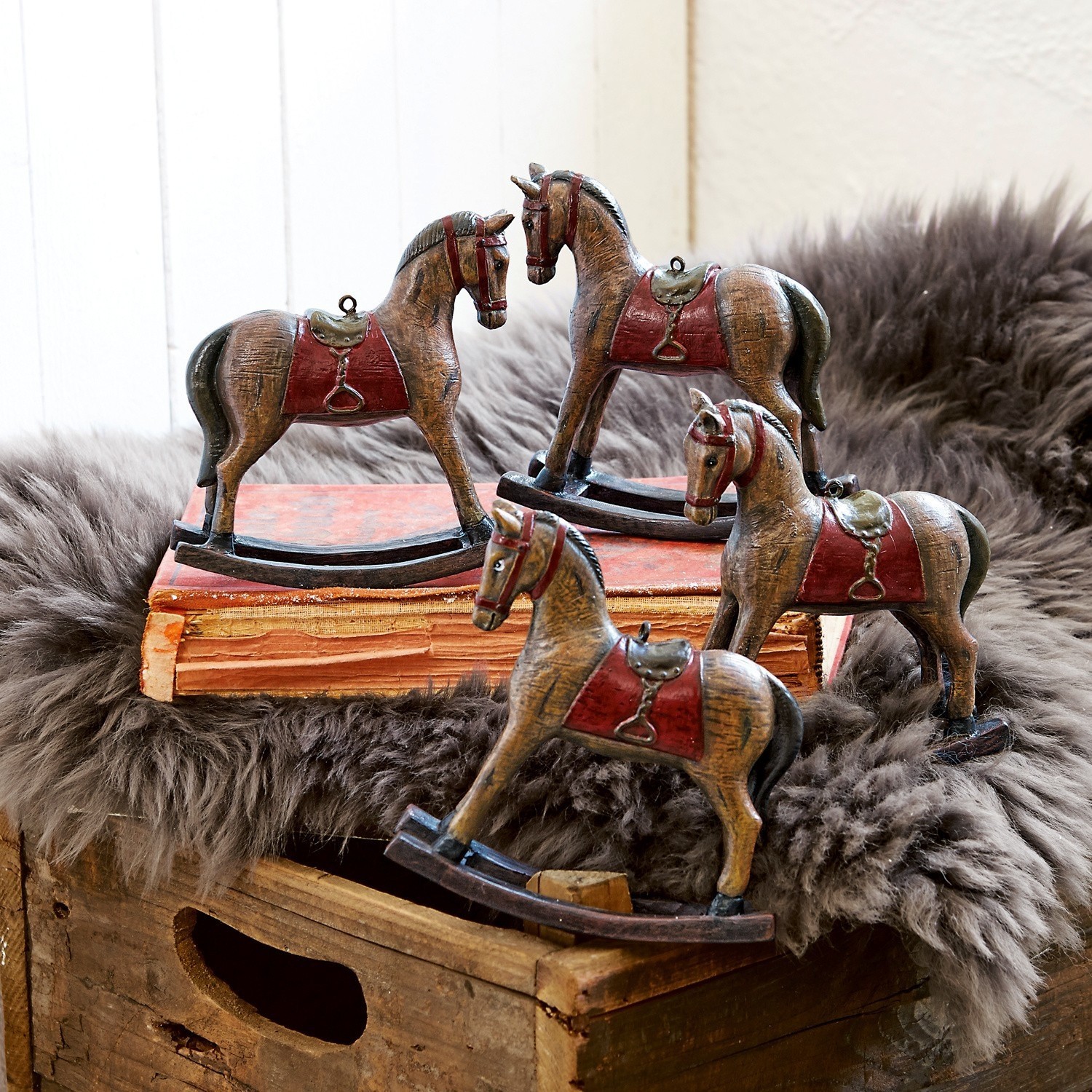 Lot de 4 chevaux décoratifs Cory Ensemble de quatre chevaux à bascule en bois marron avec selles rouges, décoration intérieure rustique.