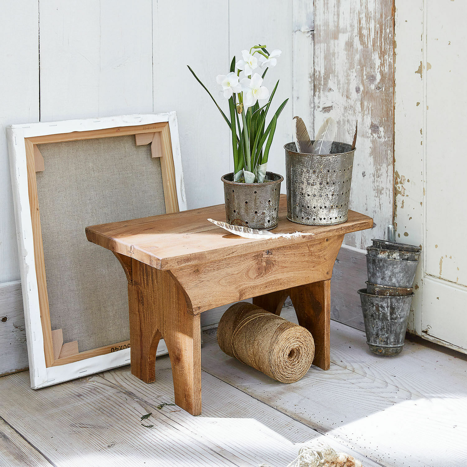 Tabouret Hoboken Petit tabouret en bois avec pots en métal et fleurs blanches sur un sol clair rustique