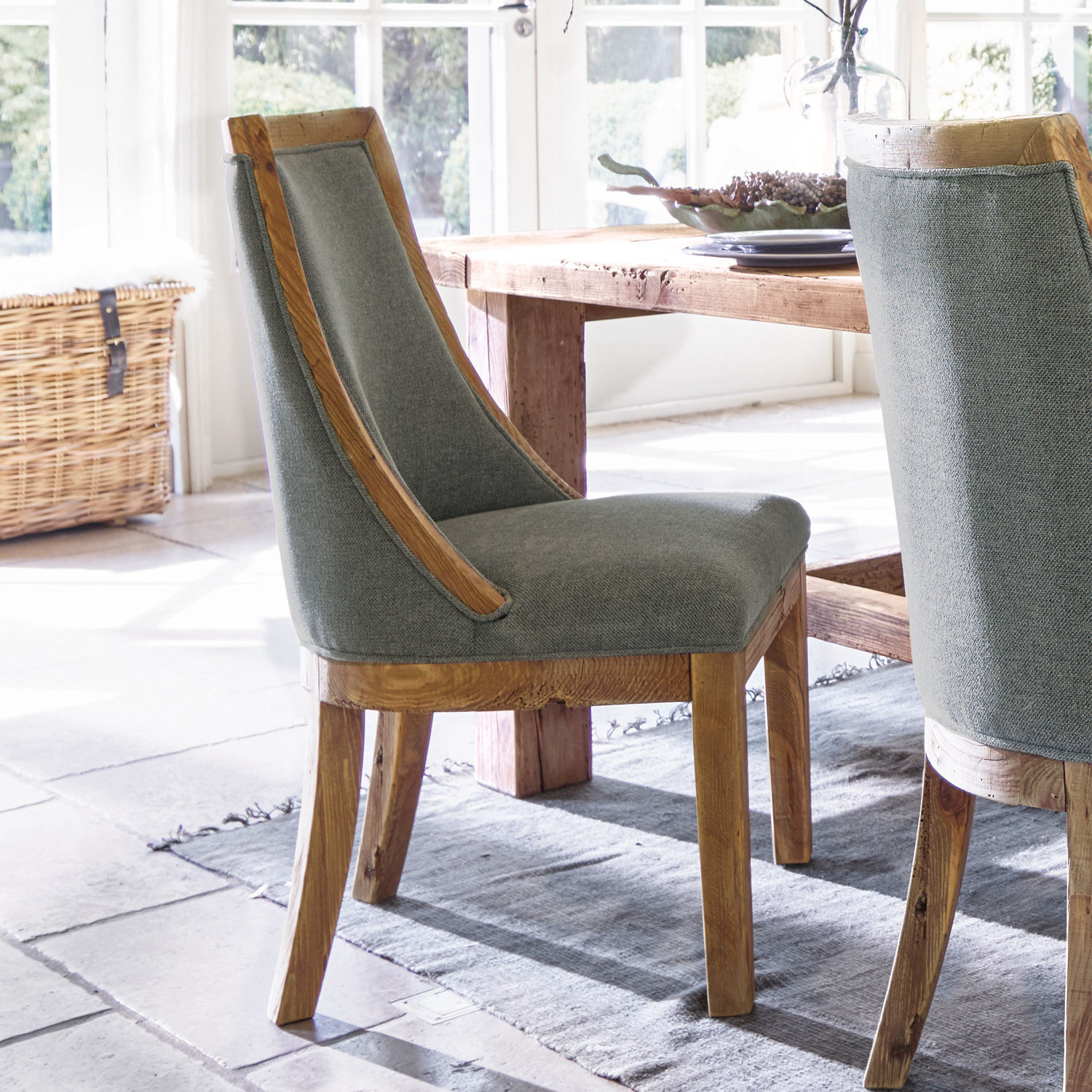 Chaise Oteley Chaise de salle à manger en bois et tissu gris dans un intérieur lumineux avec tapis naturel
