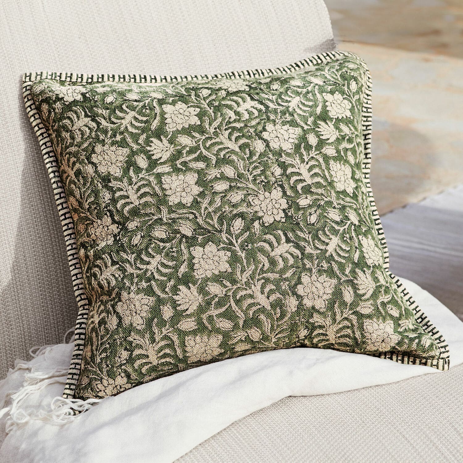 Housse de coussin Petitmagny Coussin décoratif vert en coton avec motif floral et bordure noire et blanche sur canapé clair