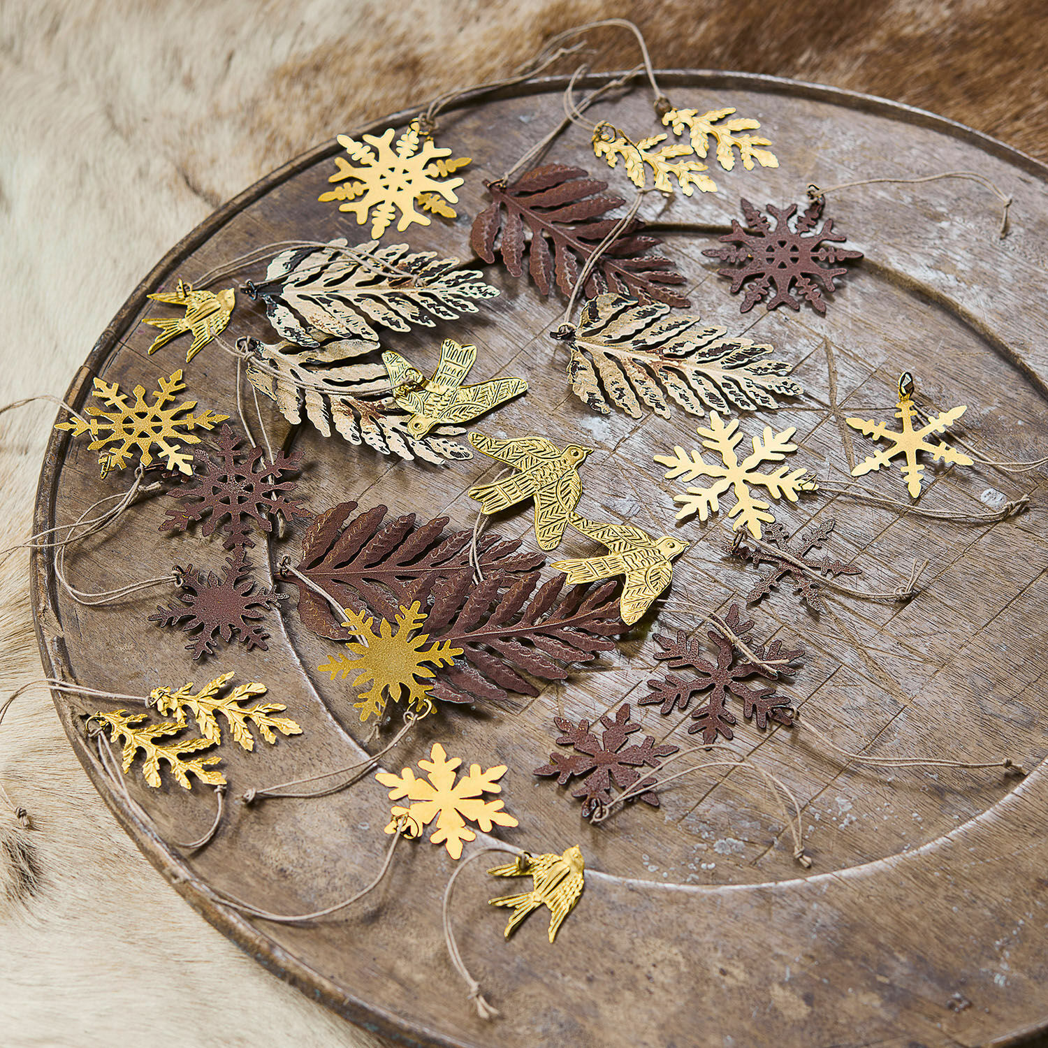 Lot de 30 décorations de Noël Mirabel Décorations métalliques en forme de feuilles, oiseaux et flocons dorés et bruns sur un plateau en bois rustique