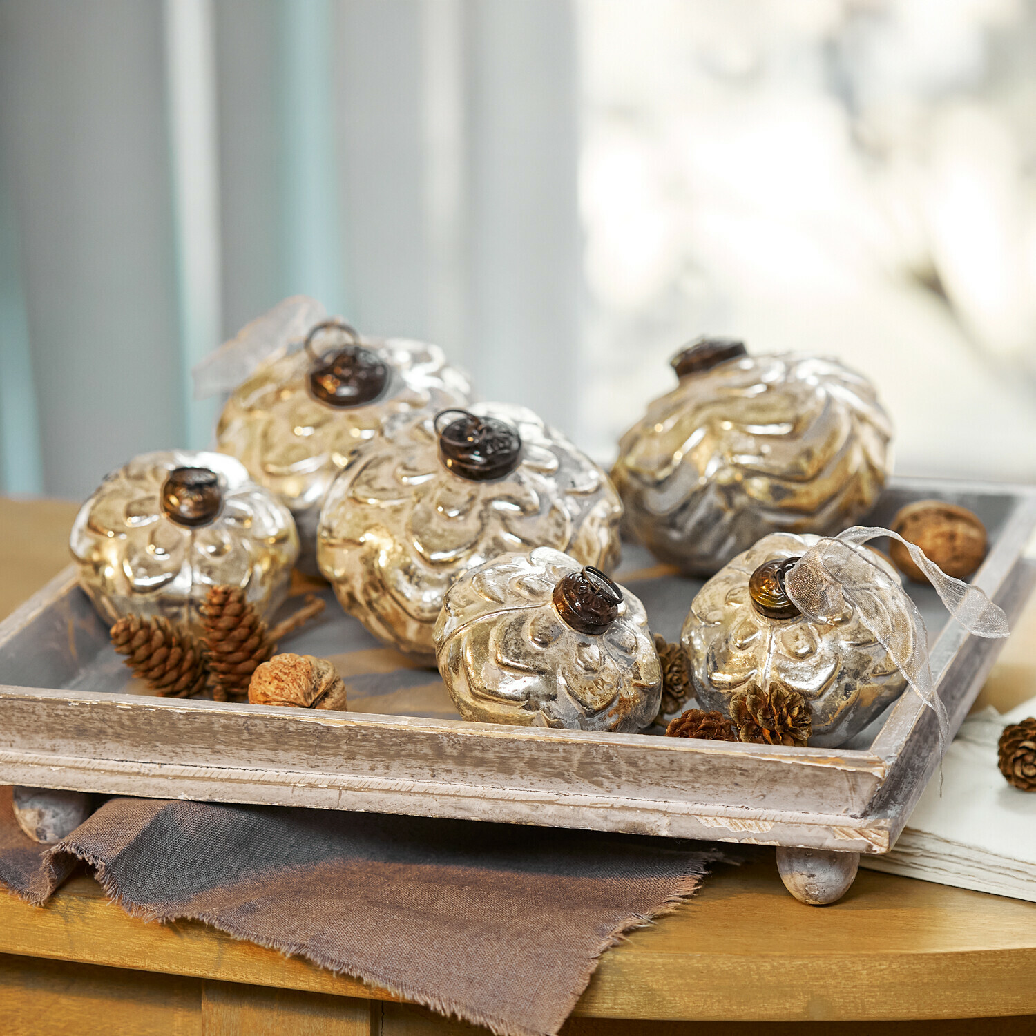 Lot de 6 boules de Noël Xilianne Décorations en verre argenté en forme de fleurs sur un plateau en bois posé sur une table