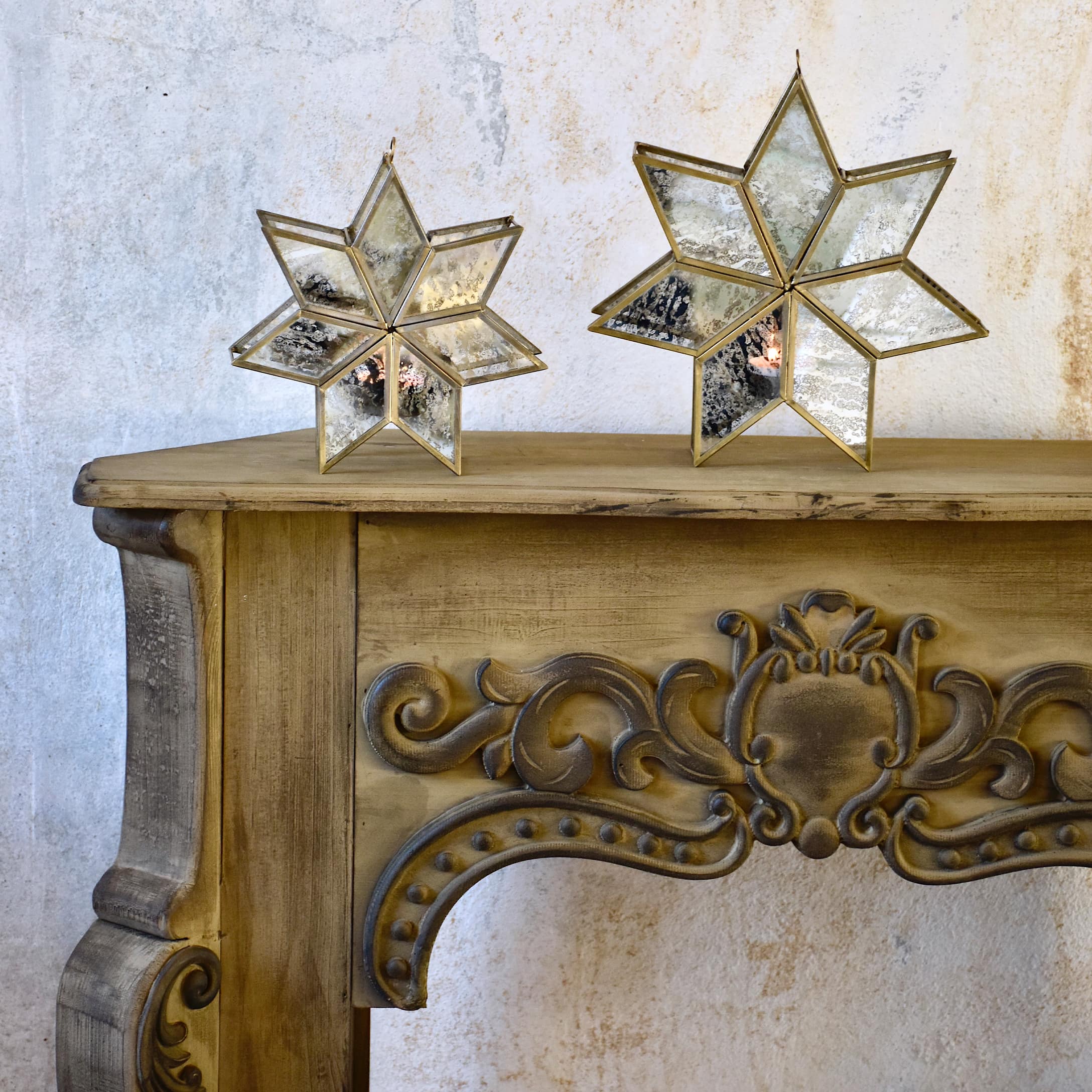 Console de cheminée en bois sculpté avec deux étoiles décoratives en verre et métal posées dessus