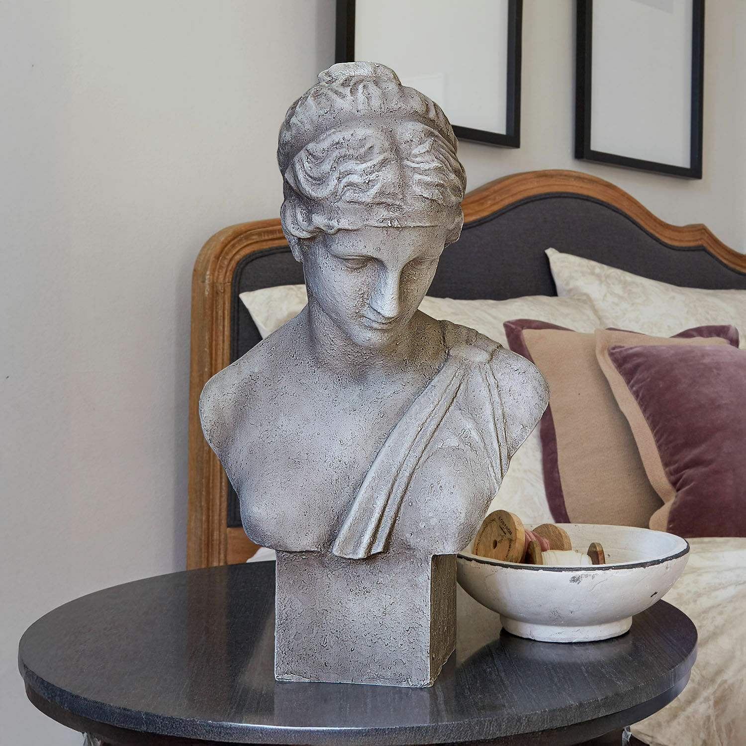 Buste Castolio Buste en pierre grise sur une table noire dans un intérieur élégant avec coussins décoratifs