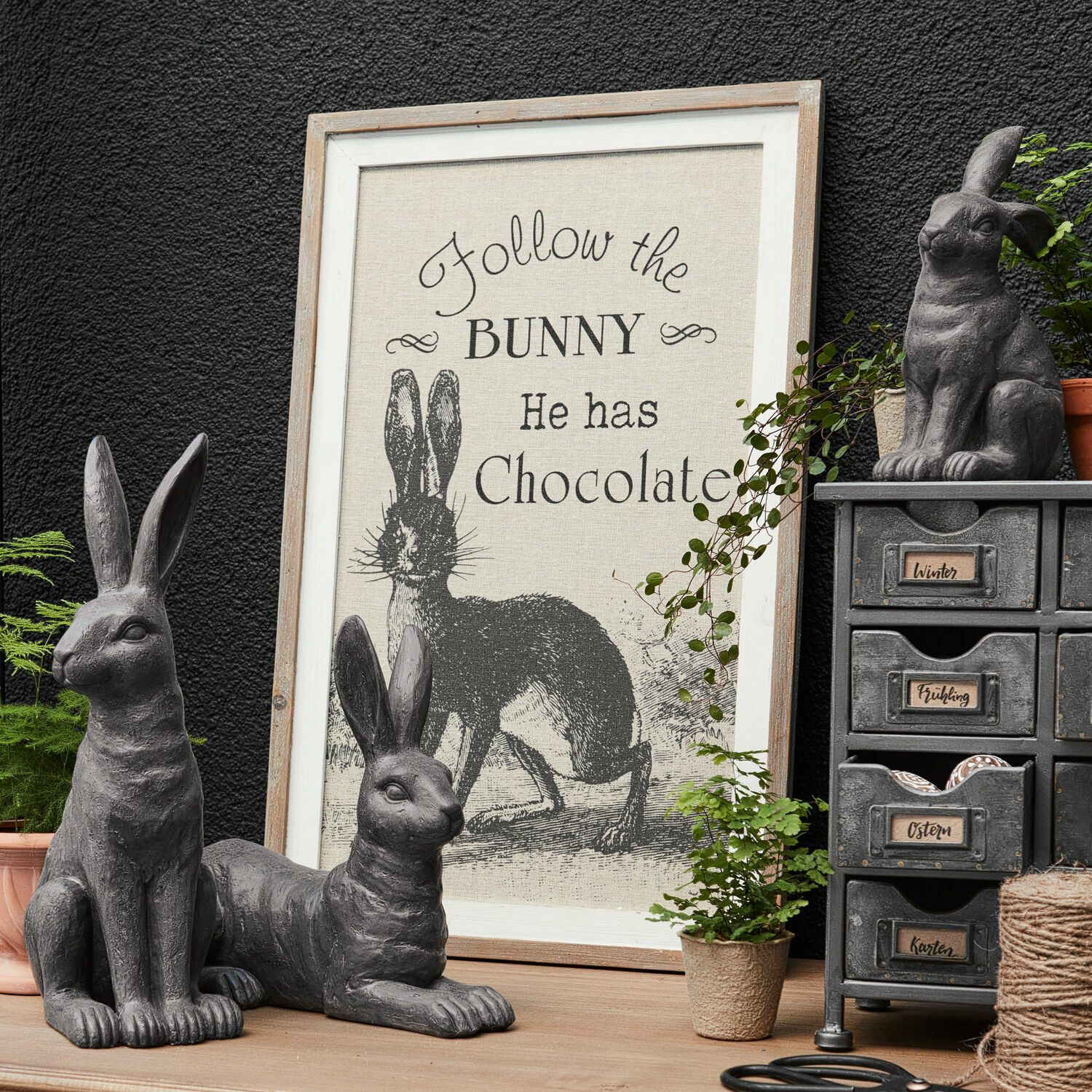 Tableau décoratif Chocolate Figurines de lapins grises décoratives avec cadre texte sur lapin et chocolat sur table en bois