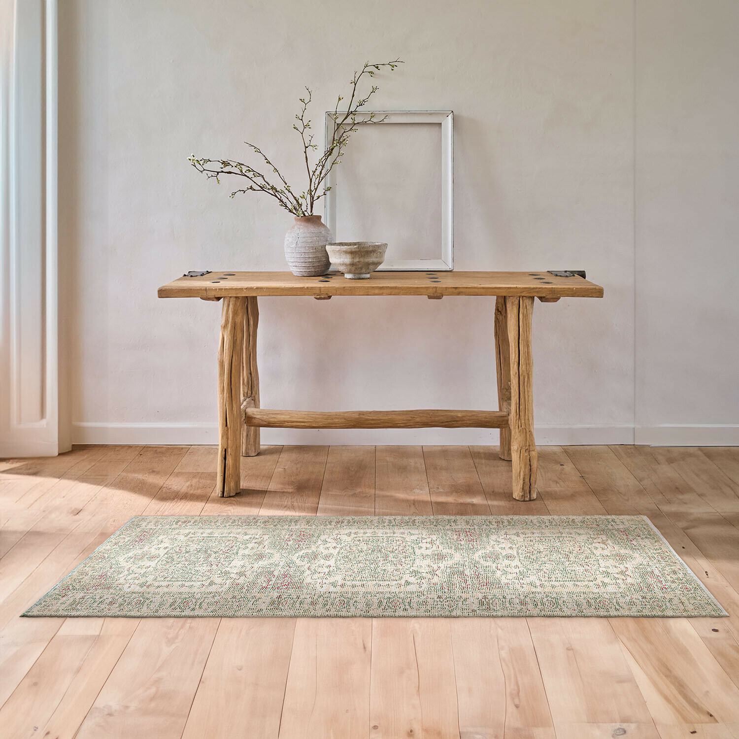 Tapis long Taranise Table en bois naturel avec vase et bol sur tapis clair dans un intérieur minimaliste lumineux