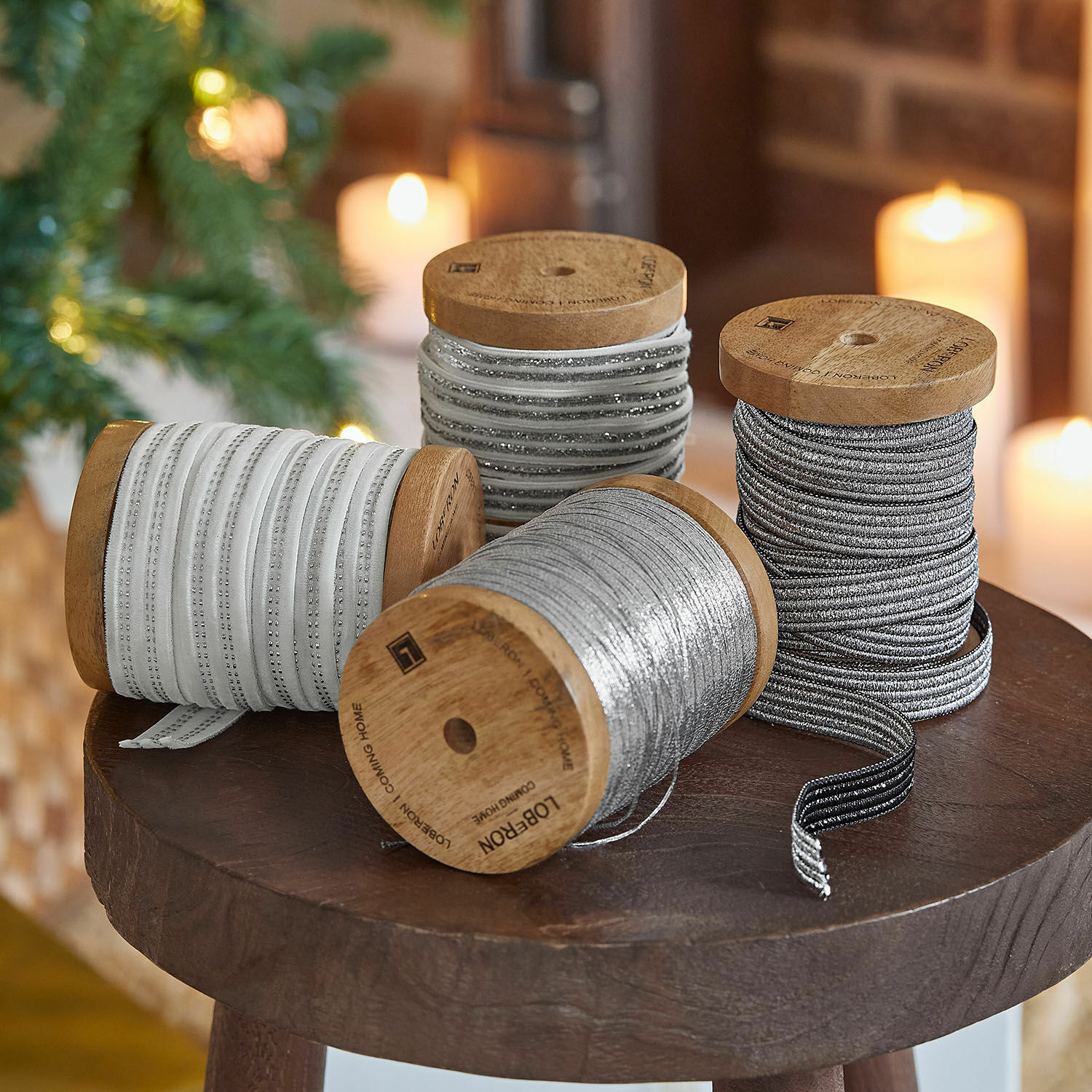Lot de 4 bobines de ruban Arceno Bobines en bois avec rubans décoratifs blancs et argentés posées sur une table en bois