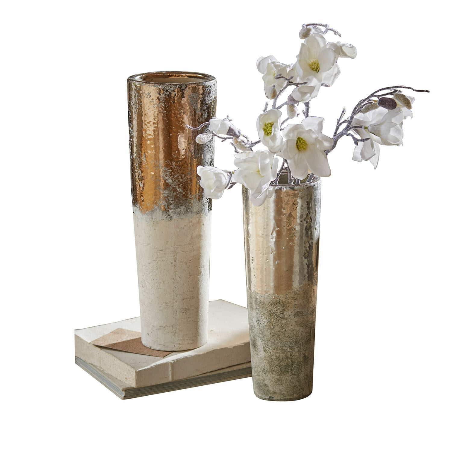 Lot de 2 vases Tameena Deux grands vases métalliques dorés et argentés posés sur des livres avec des fleurs blanches décoratives