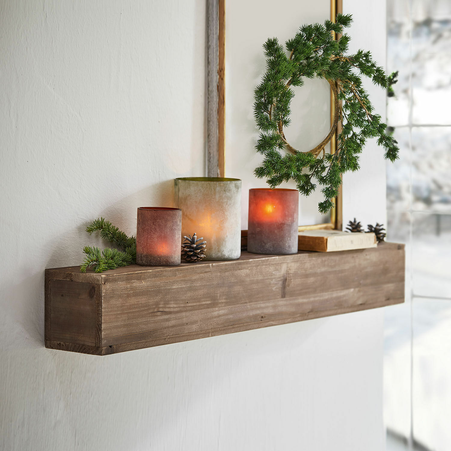 Étagère murale Visayas Étagère murale en bois avec bougies décoratives et couronne verte dans un intérieur lumineux