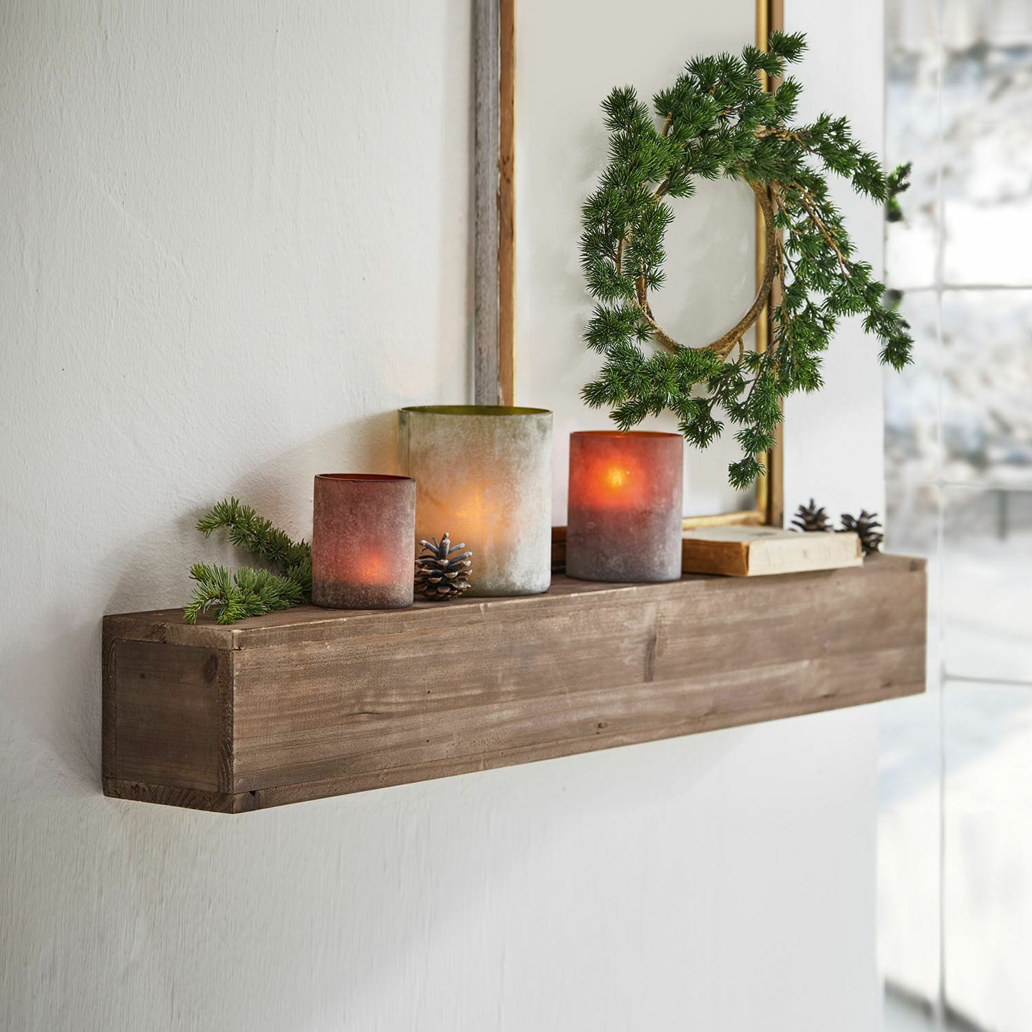 Étagère murale Visayas Étagère murale en bois avec bougies décoratives et couronne verte dans un intérieur lumineux