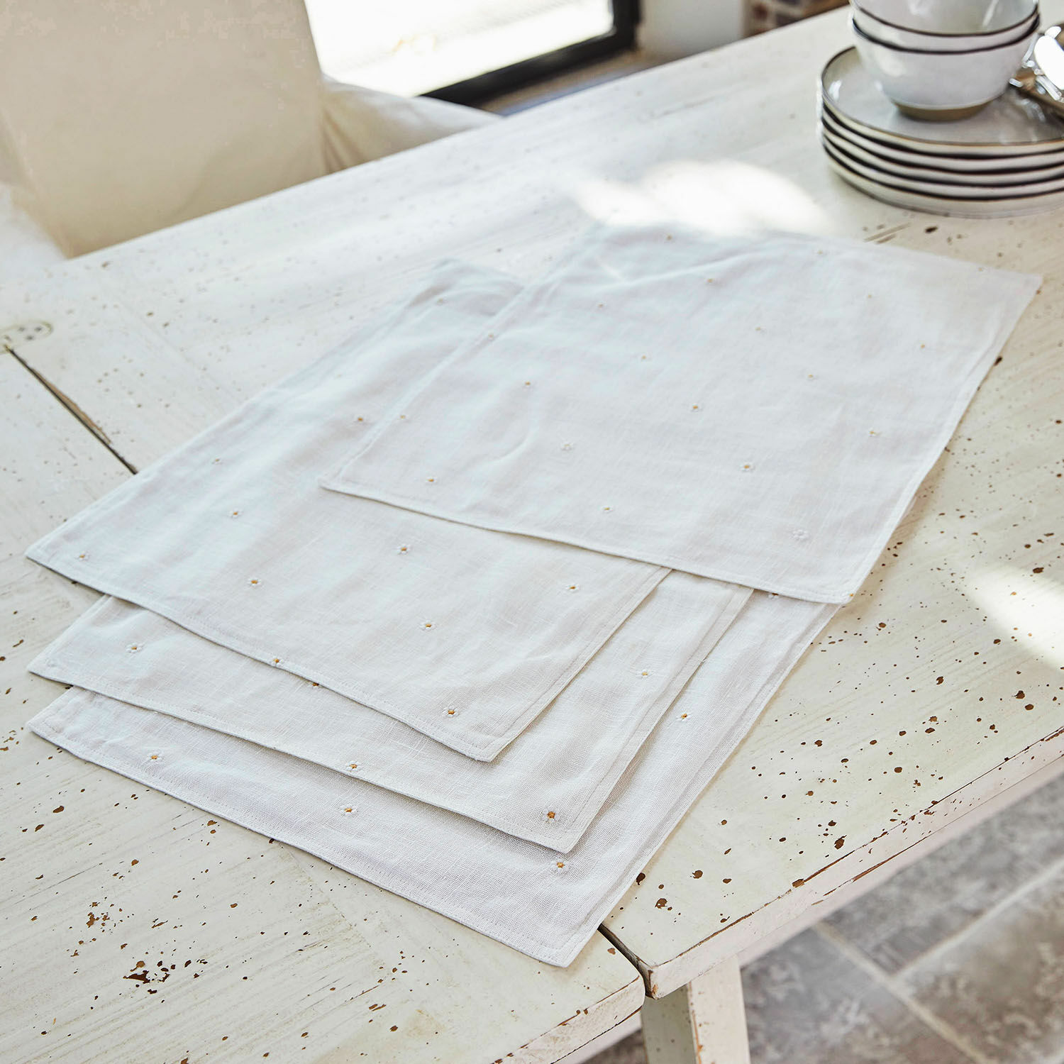 Serviettes en lin blanc avec broderie délicate sur une table rustique, décoration de table élégante