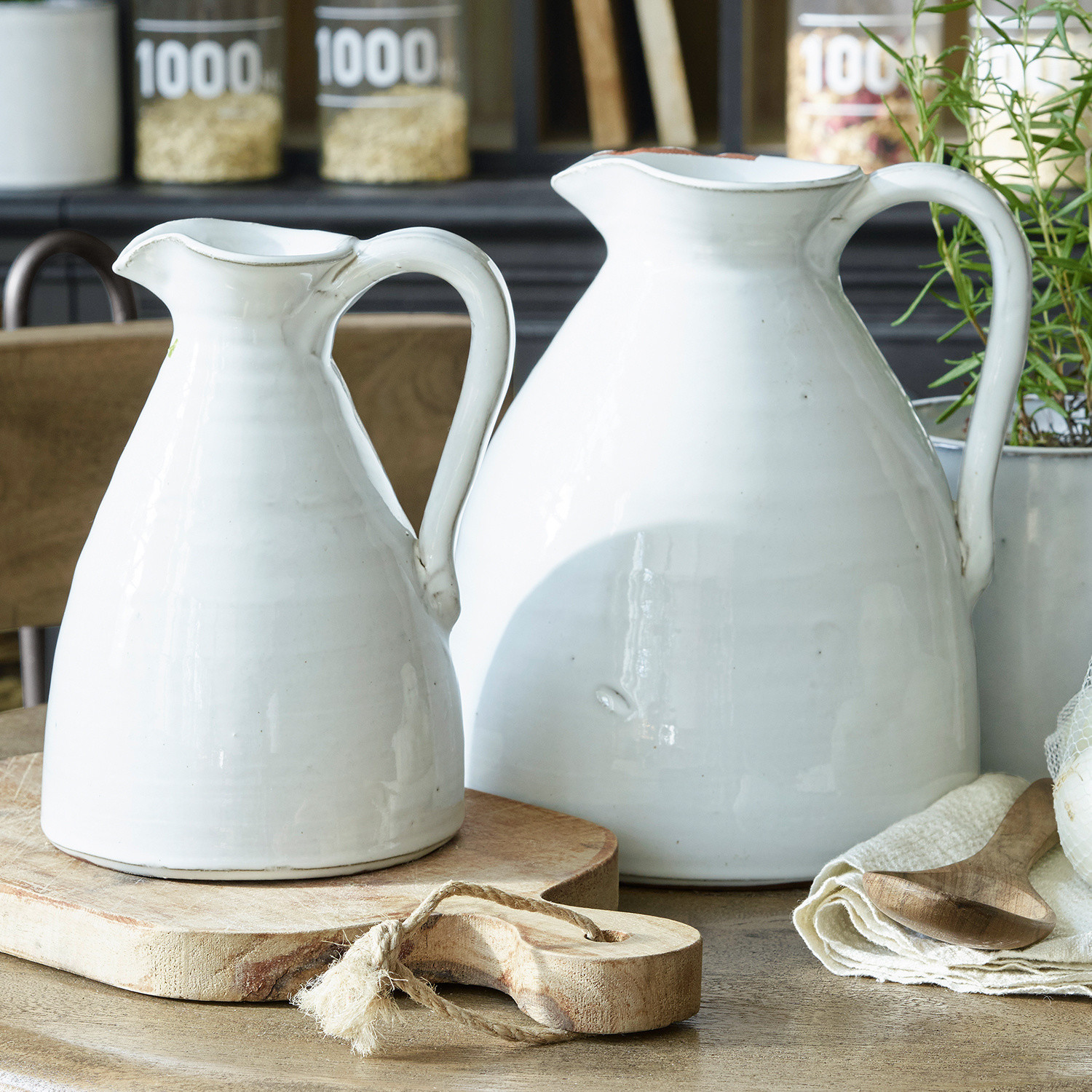 Lot de 2 vases Yarick Deux pichets en céramique blanche posés sur une planche en bois dans une cuisine rustique