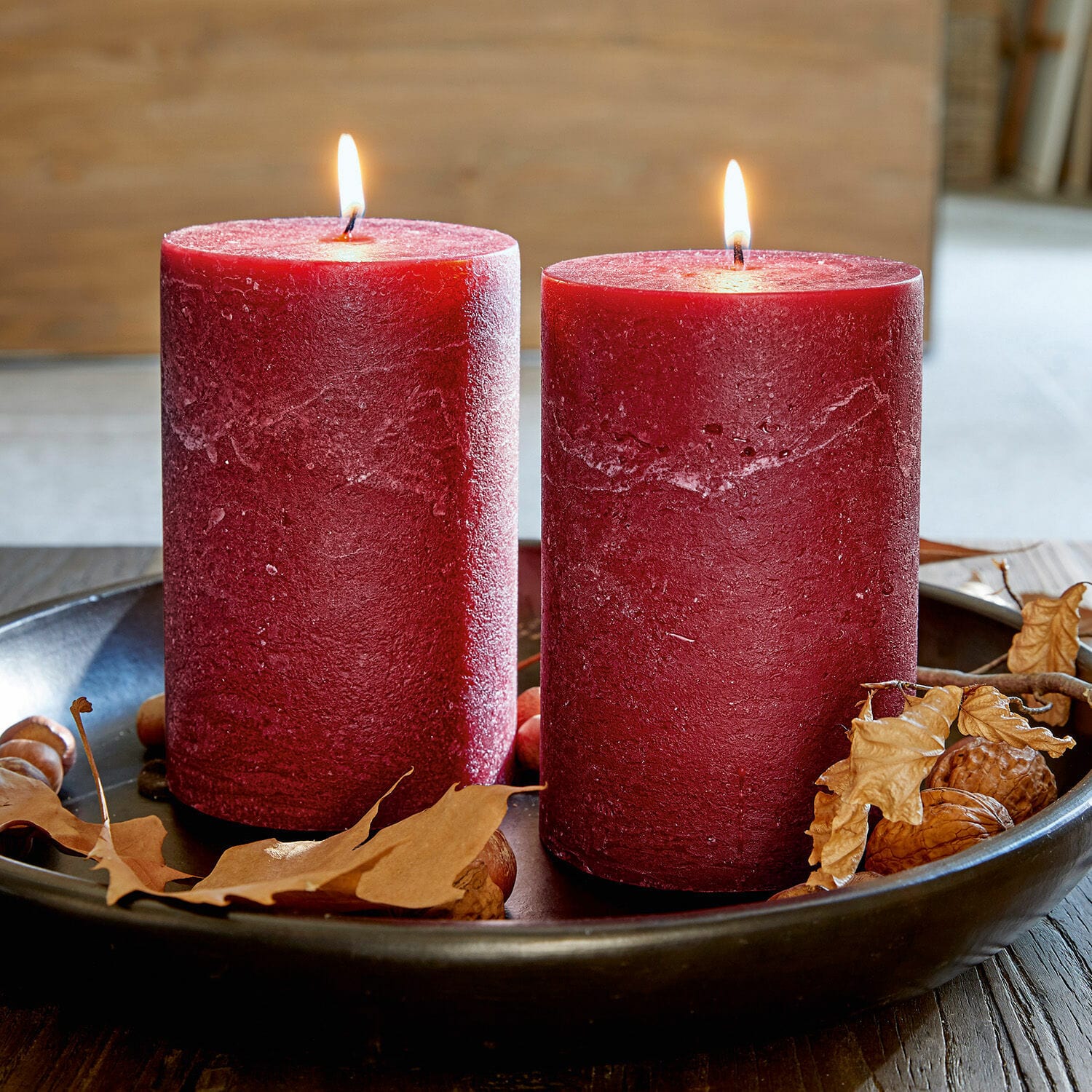 Lot de 2 bougies Oviedo Deux bougies rouges en cire sur un plateau noir avec feuilles sèches et noix, décoration automnale