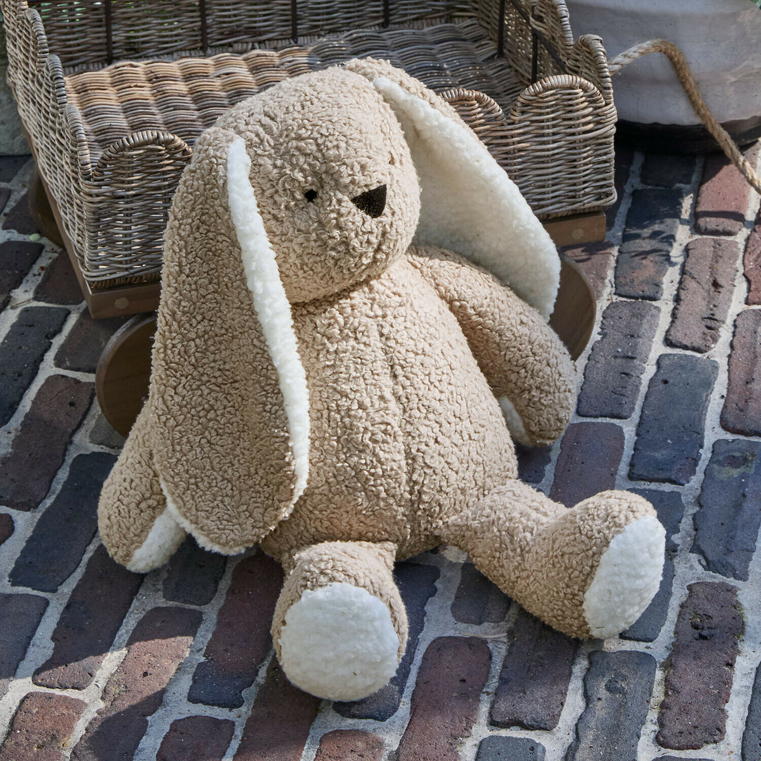Peluche Fluffernap Lapin en peluche beige doux avec oreilles et pattes blanches posé sur un sol en briques